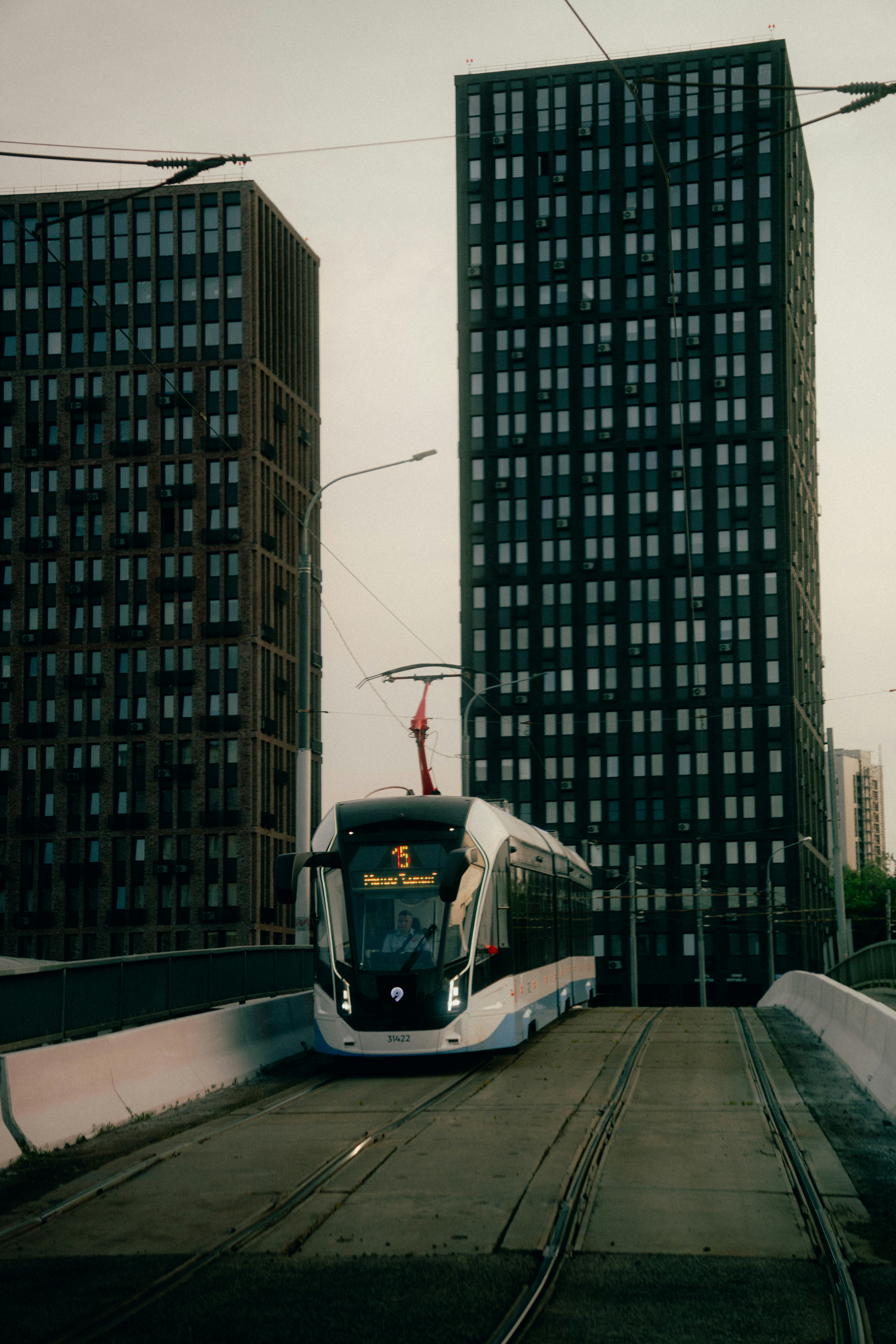 Um bonde moderno viaja entre prédios altos.