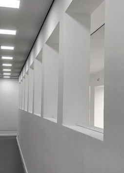 Modern white hallway with square openings and ceiling lights