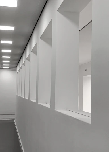 Modern white hallway with square openings and ceiling lights
