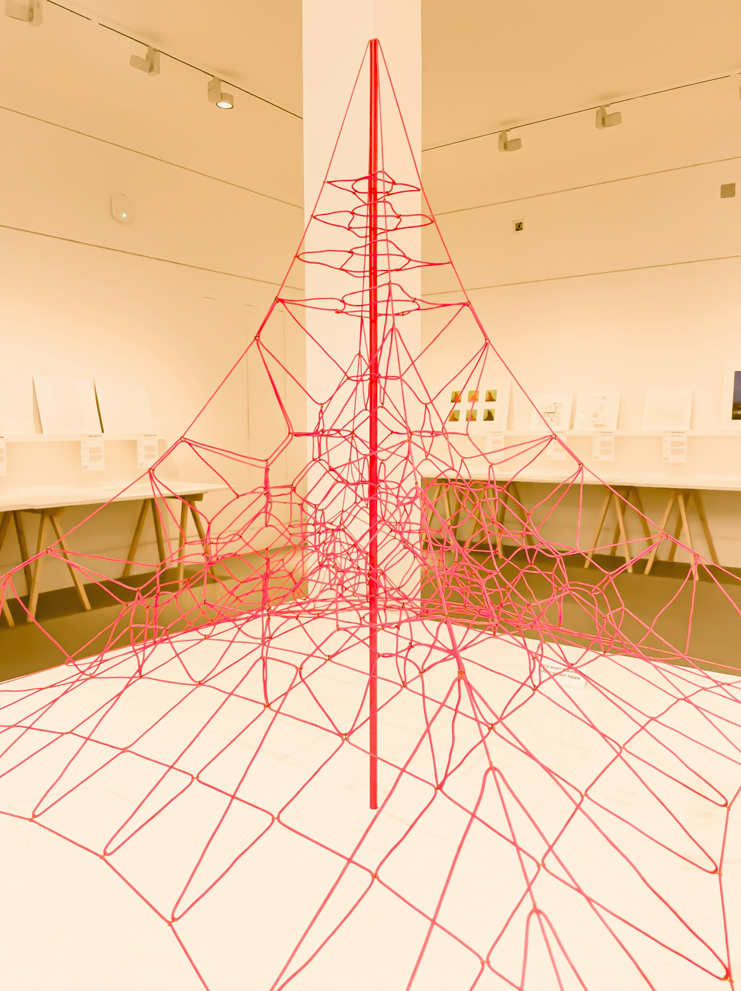 A large pink rope sculpture in a white room