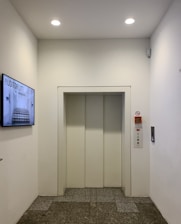 Modern elevator doors in a clean white hallway.