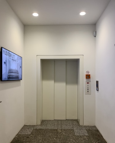 Modern elevator doors in a clean white hallway.