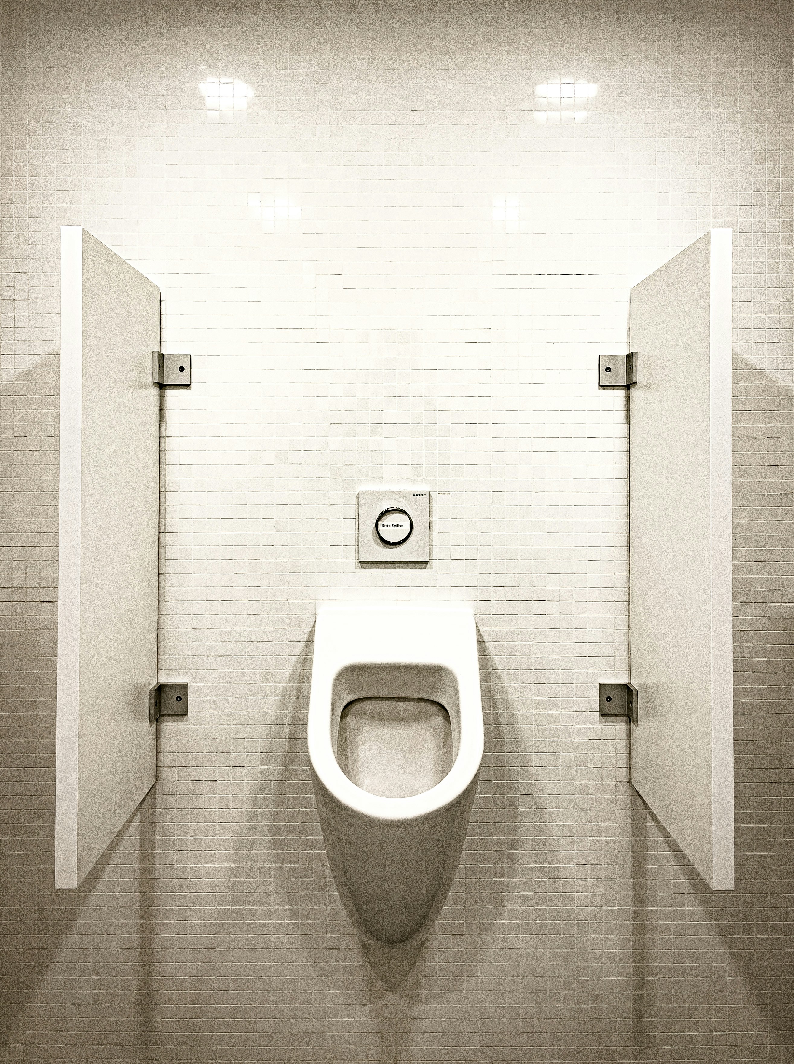 A white urinal with partition walls in a restroom