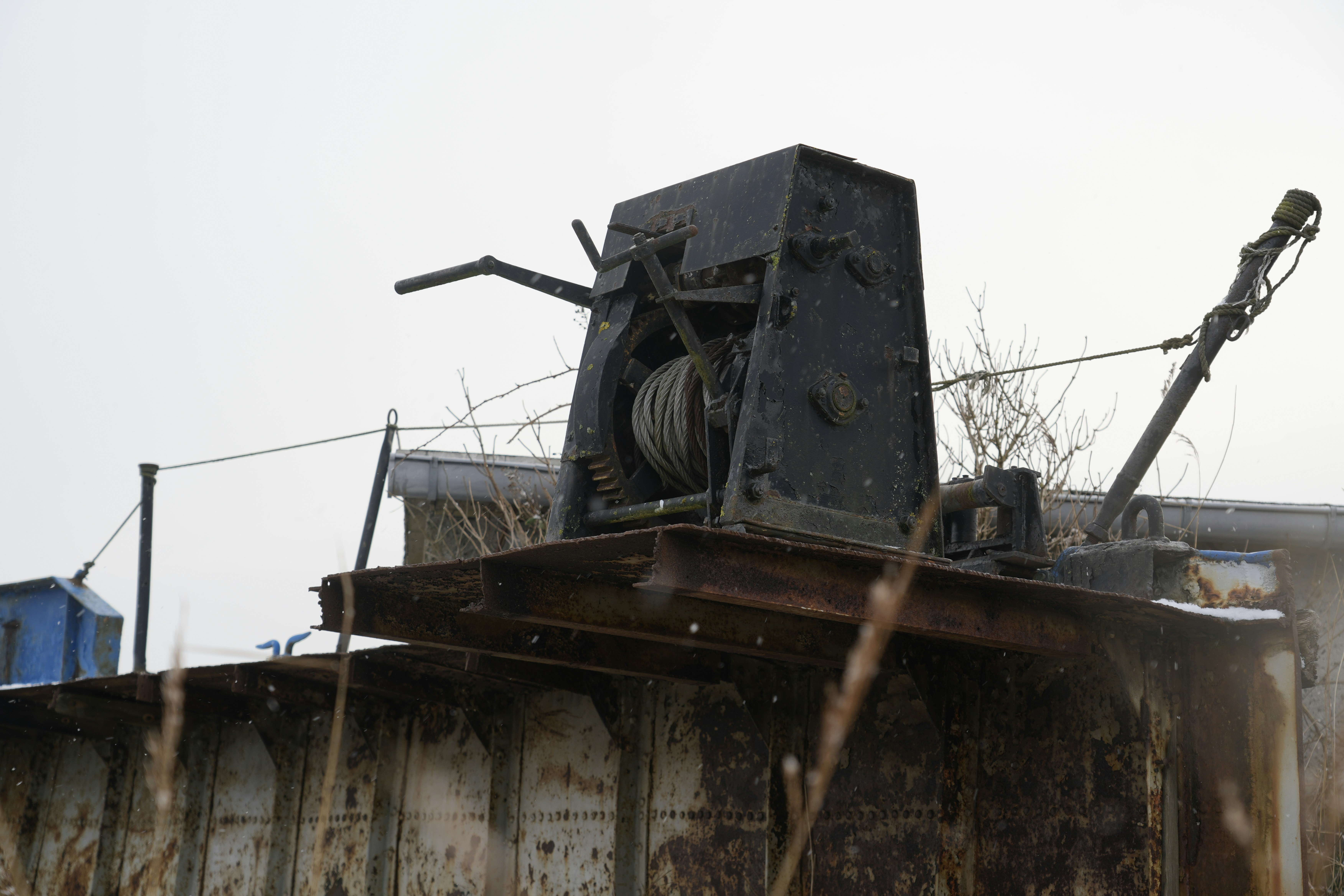 Old industrial winch on a rusty metal structure.