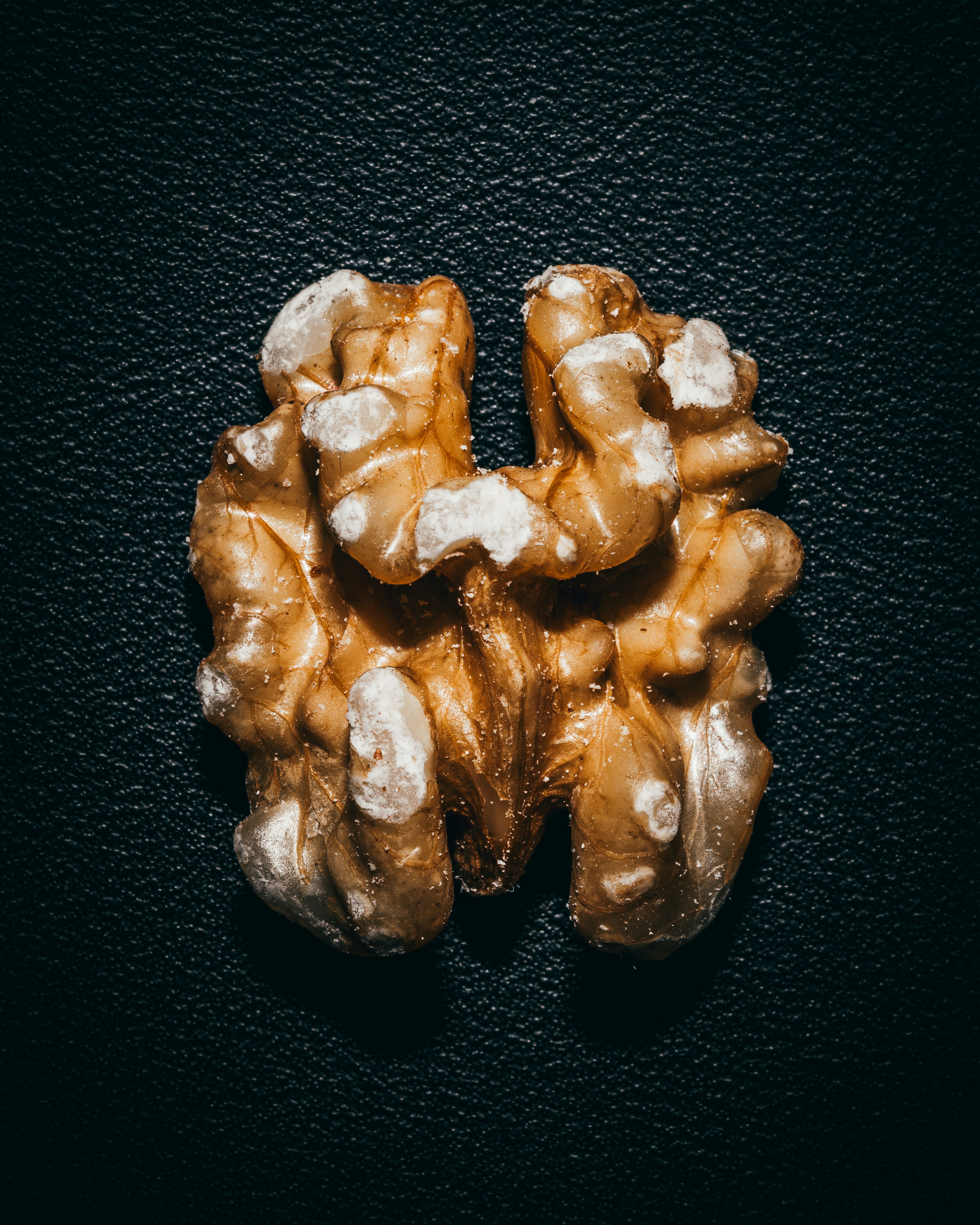 A single walnut half on a dark surface