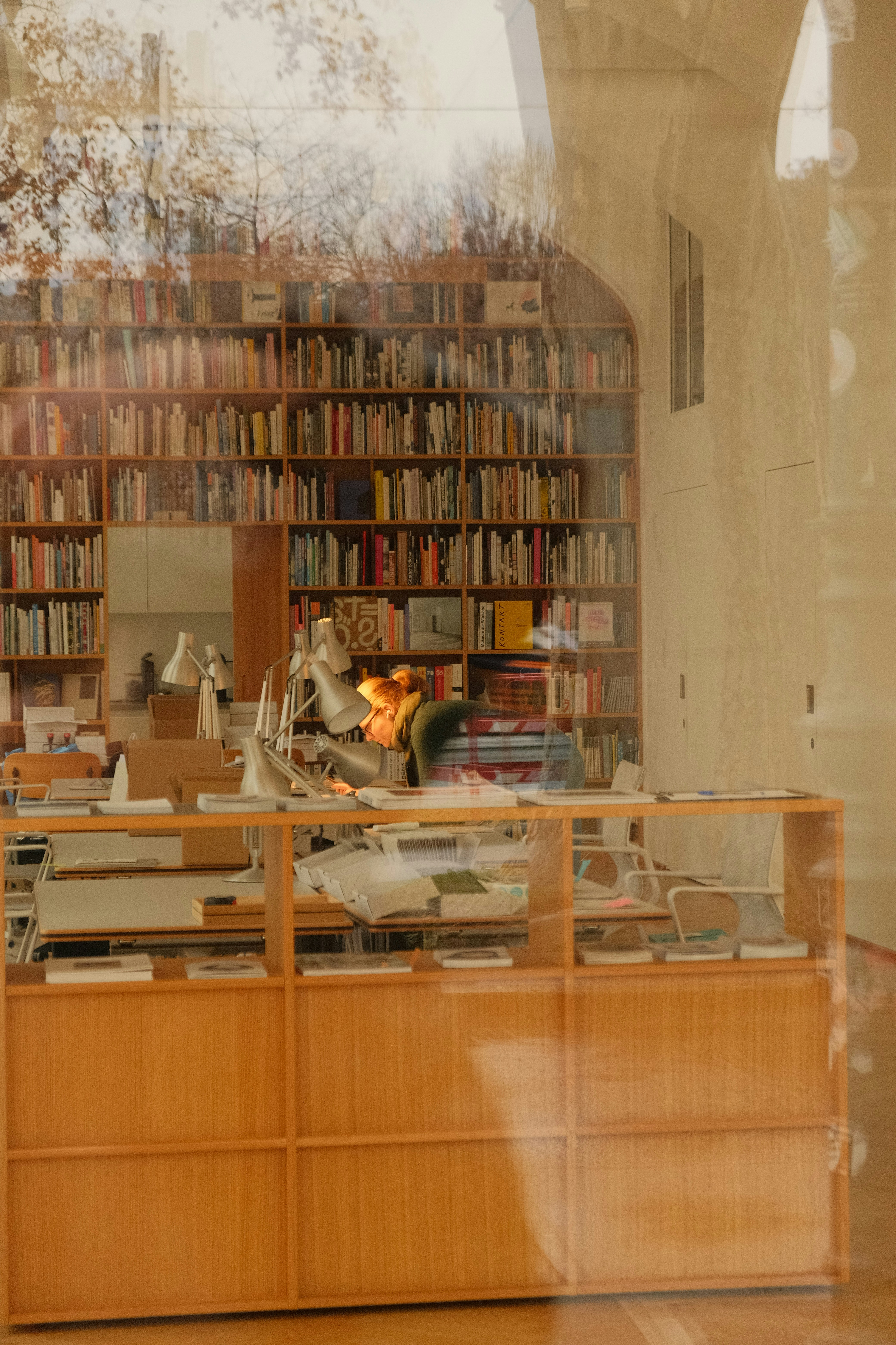 Donna che lavora a una scrivania di legno circondata da alte librerie.