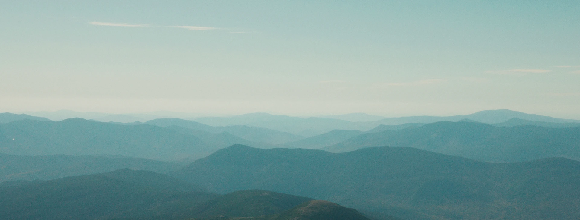 Layered blue mountain ranges under a pale sky