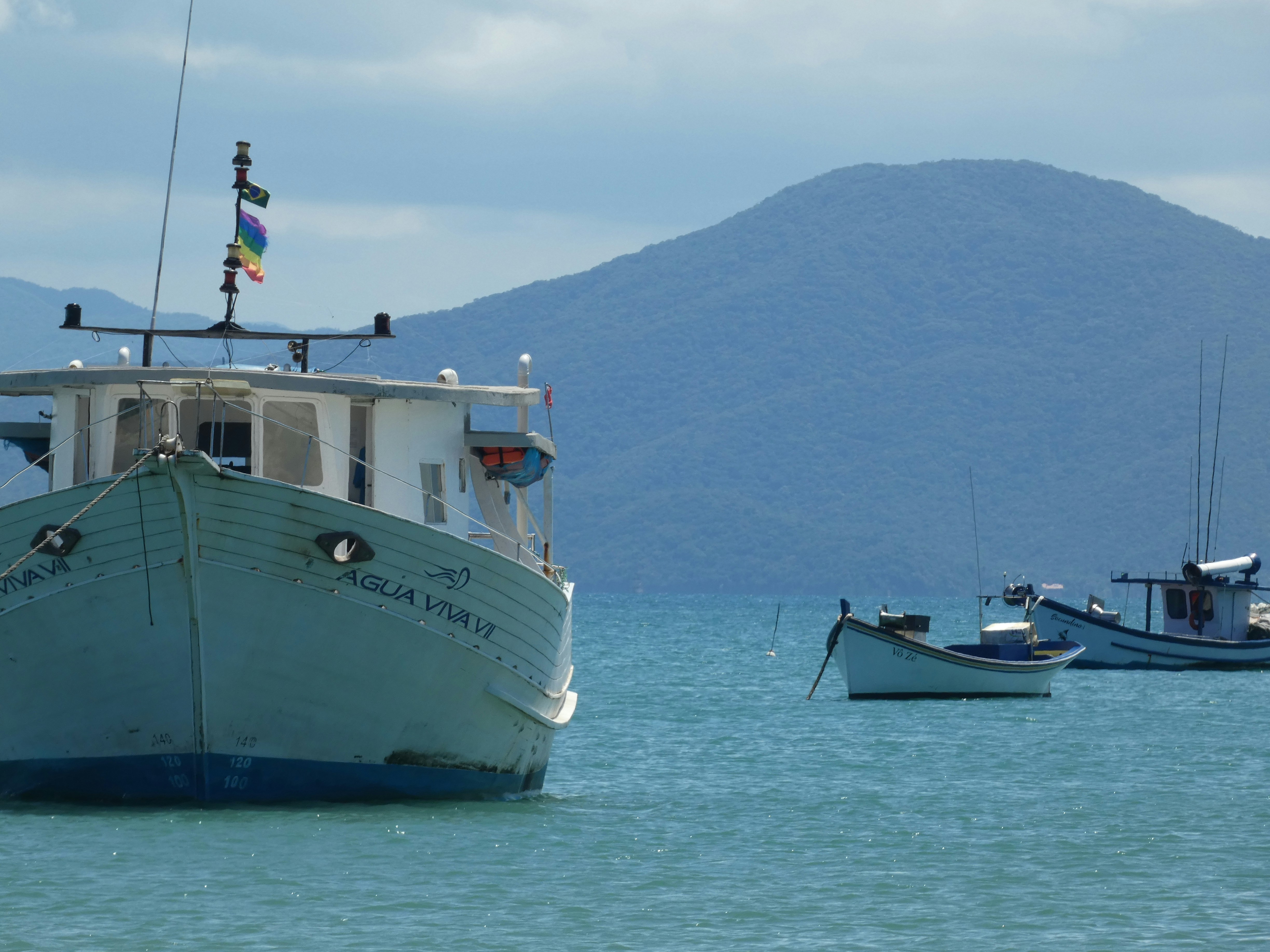 Fishing boats float on the calm blue sea.