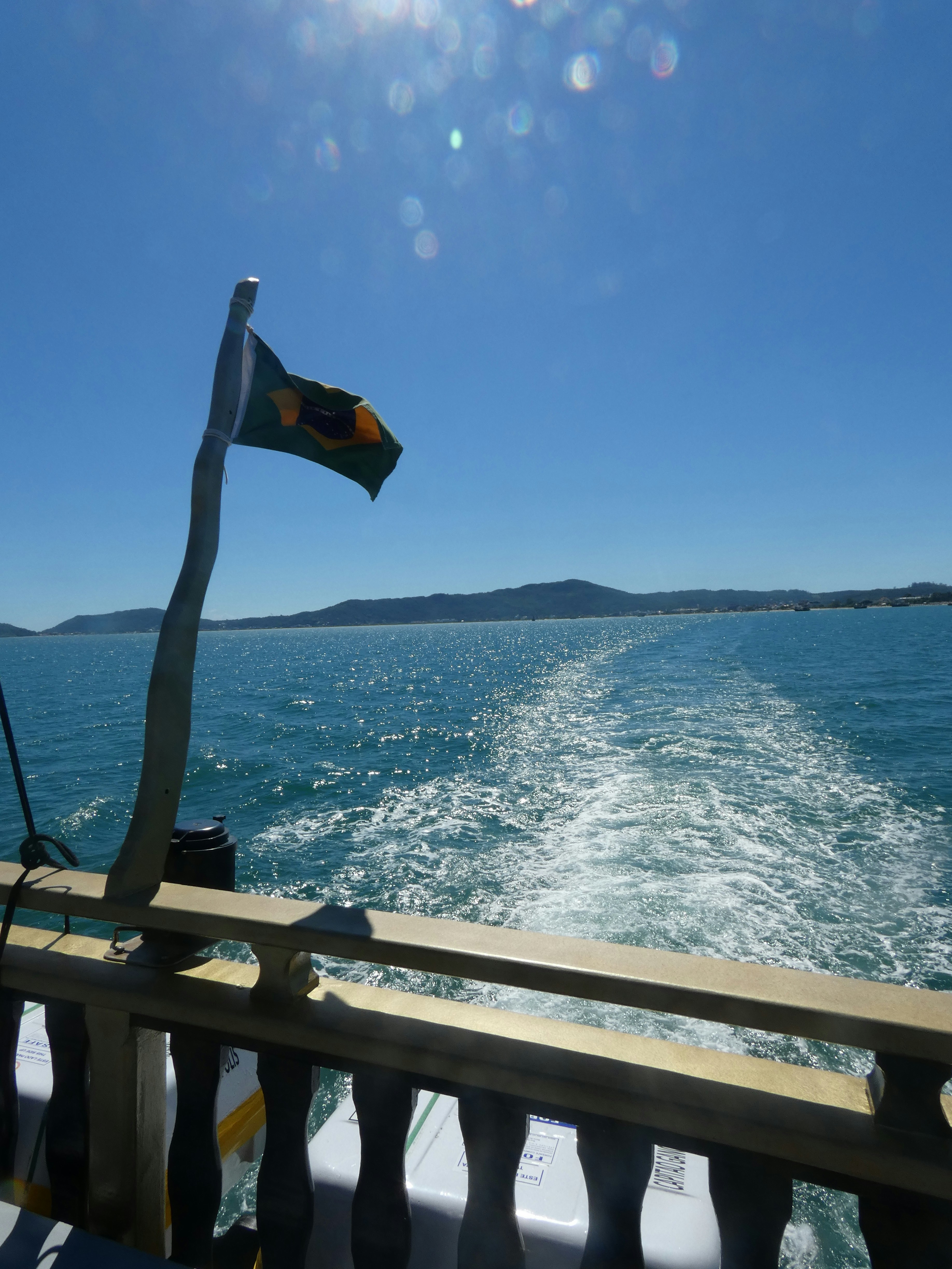 Bandiera brasiliana su una barca che naviga attraverso oceano blu.
