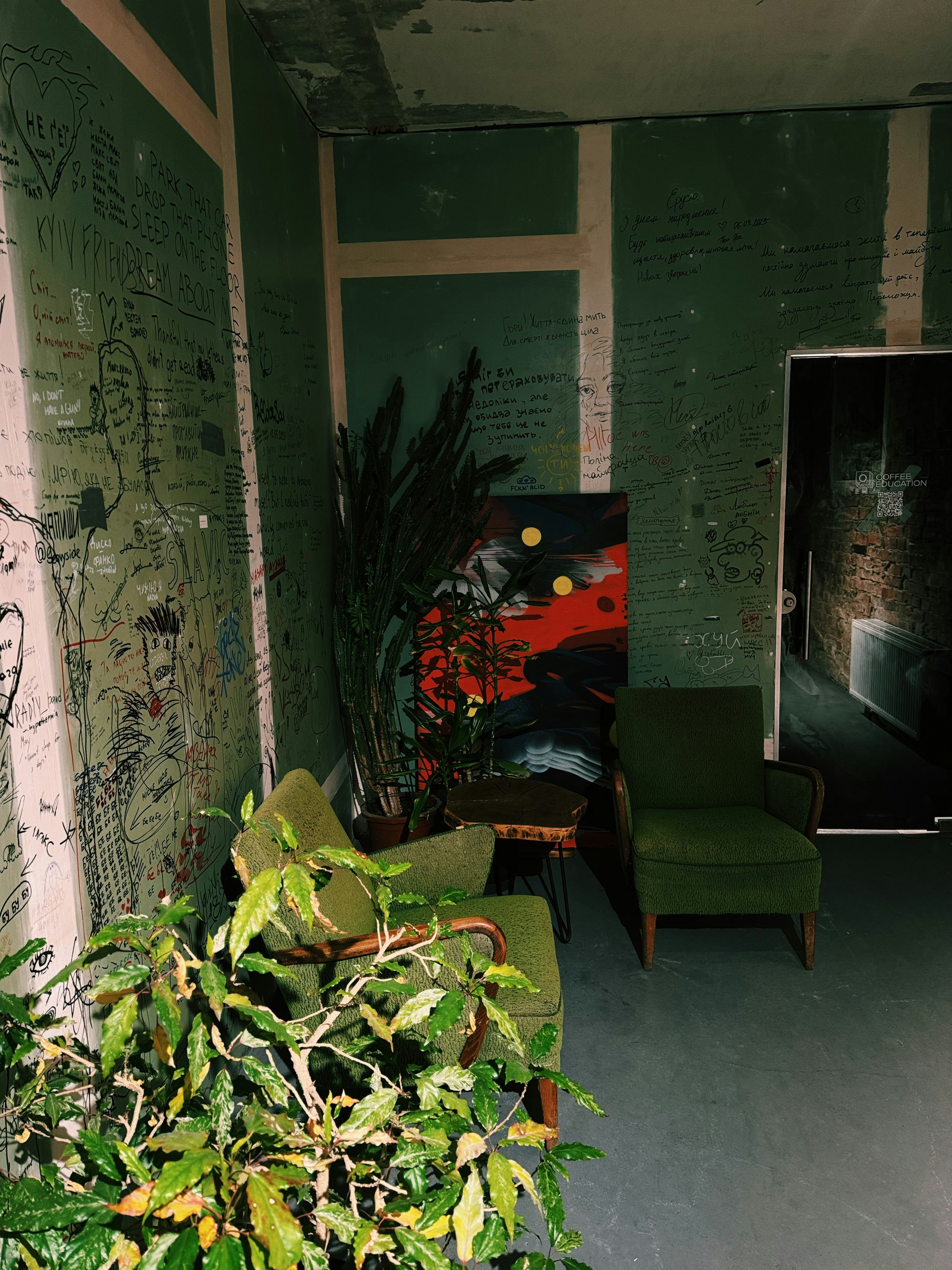 Grüne Stühle und Pflanzen in einem Raum mit Kunst.