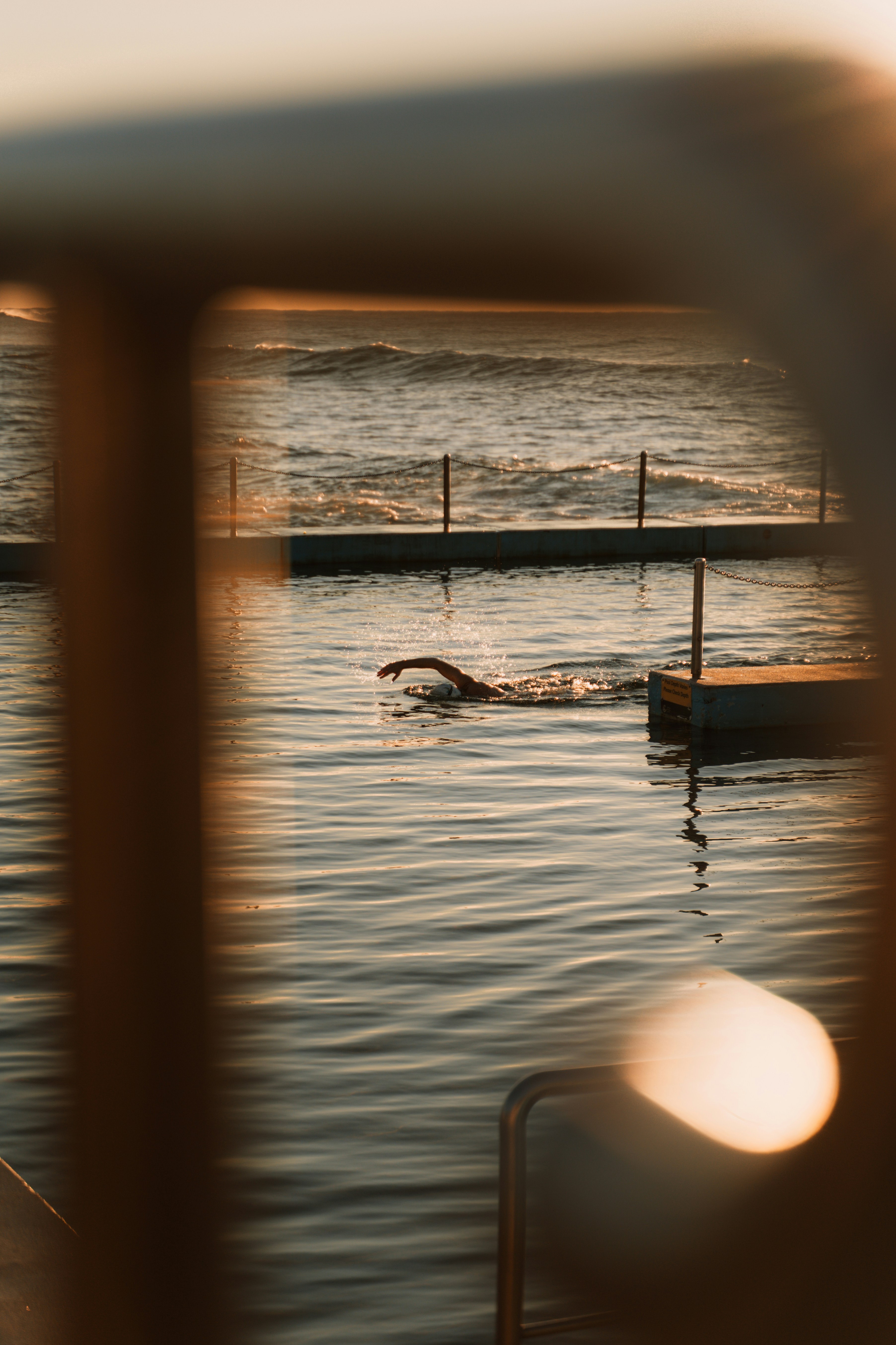 Nadador en una piscina oceánica al atardecer