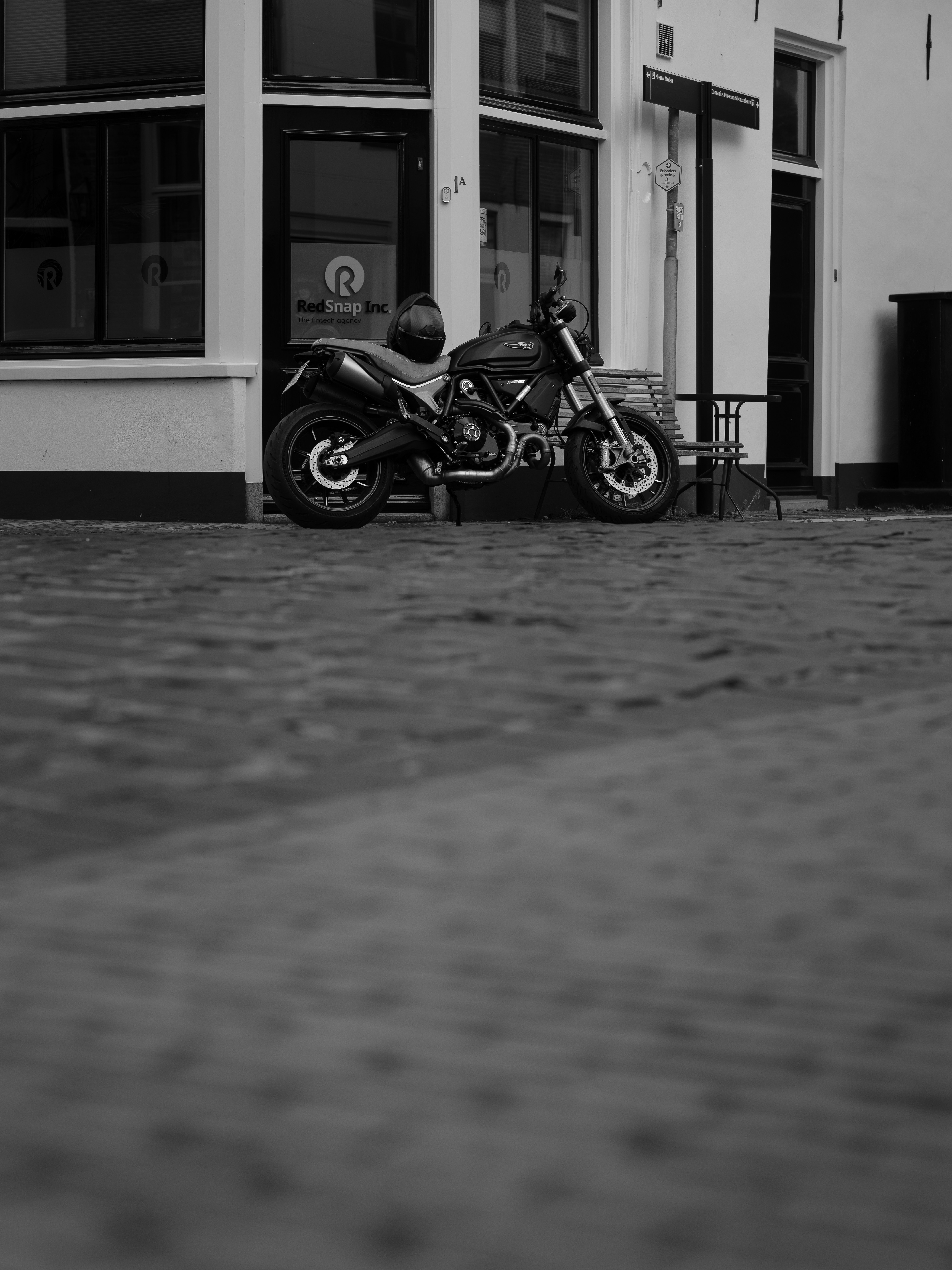 A black motorcycle parked on a cobblestone street.