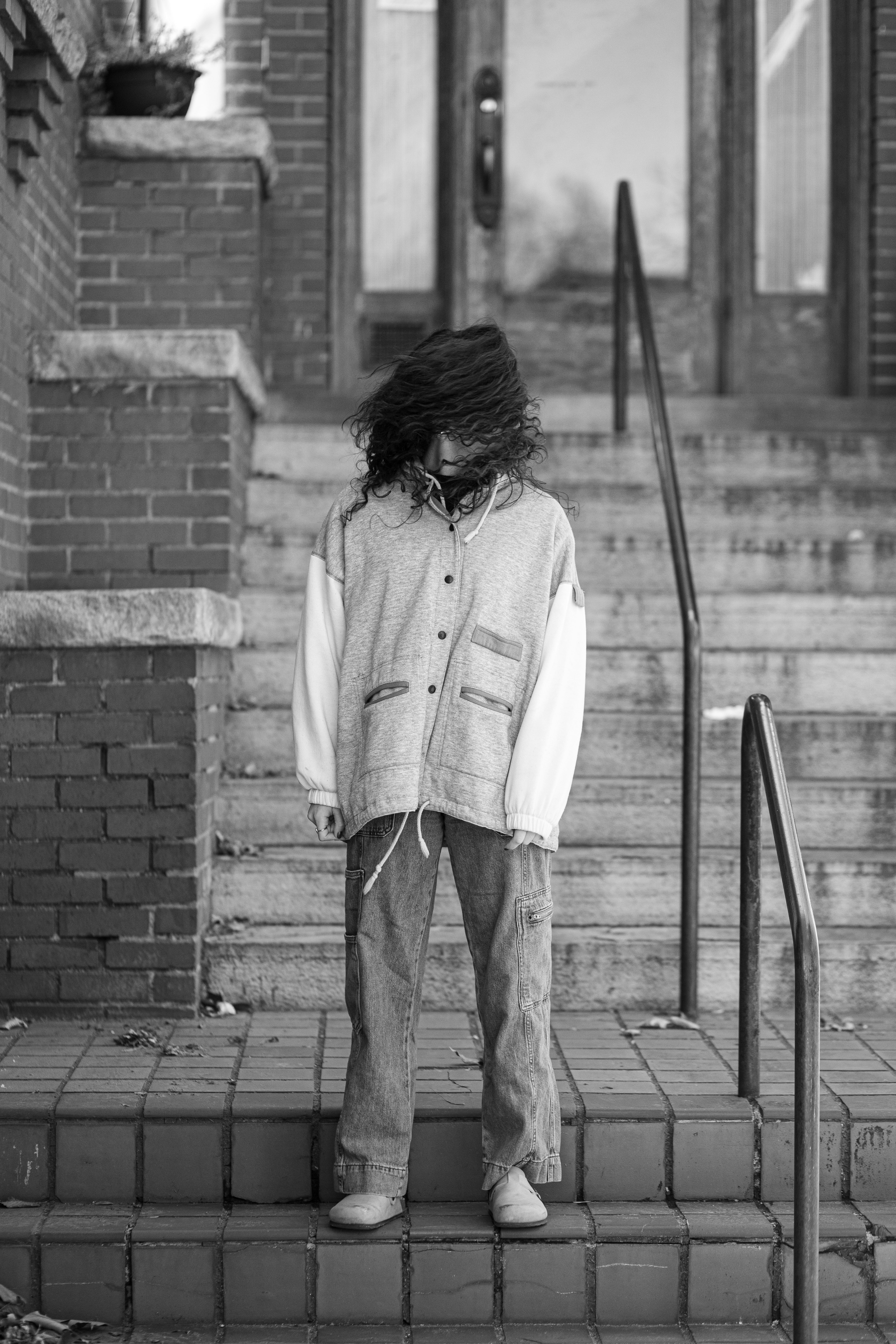 Una persona sta sui gradini con i capelli che coprono il viso.