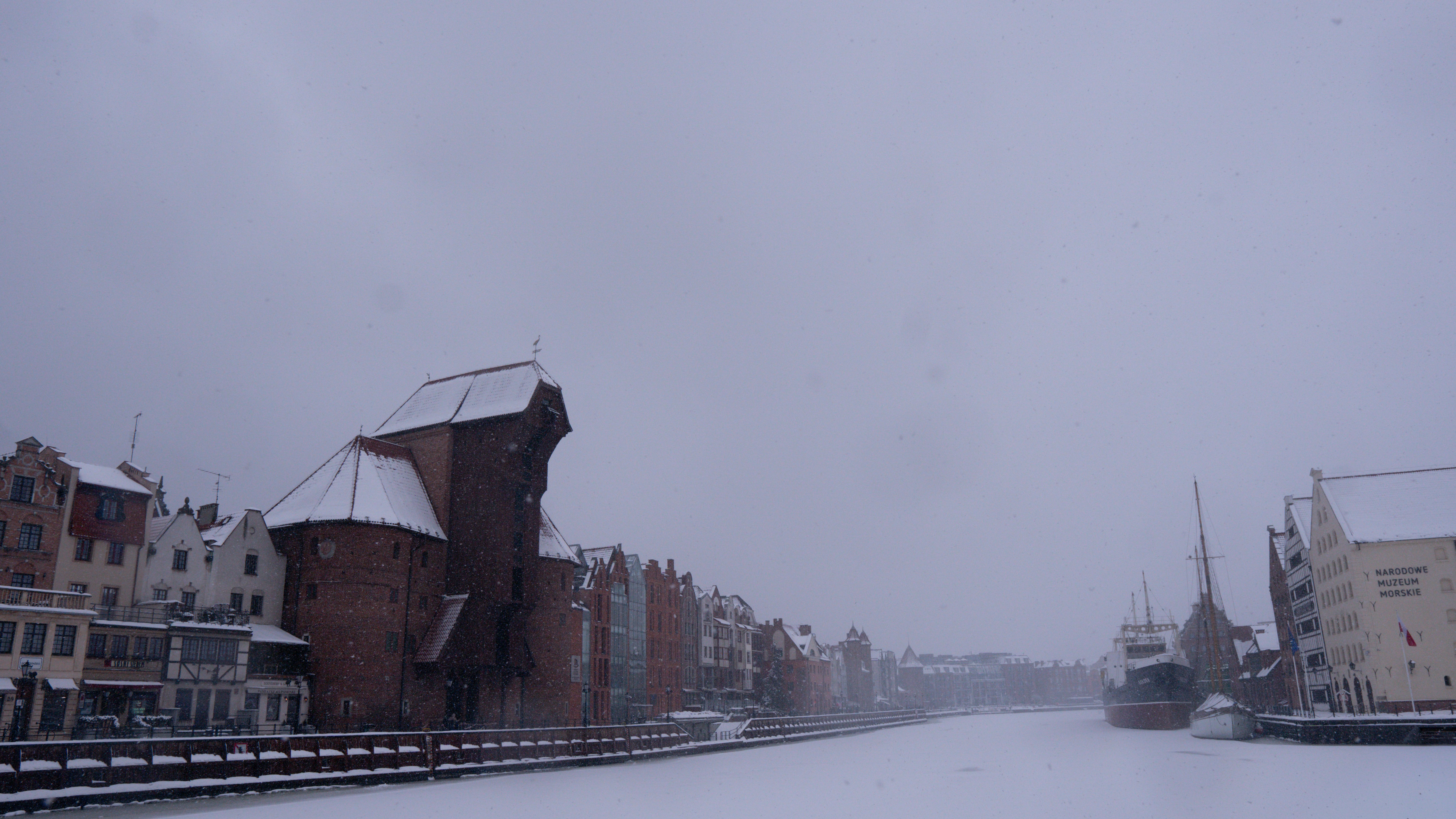 Snowy canal with historic buildings and cranes