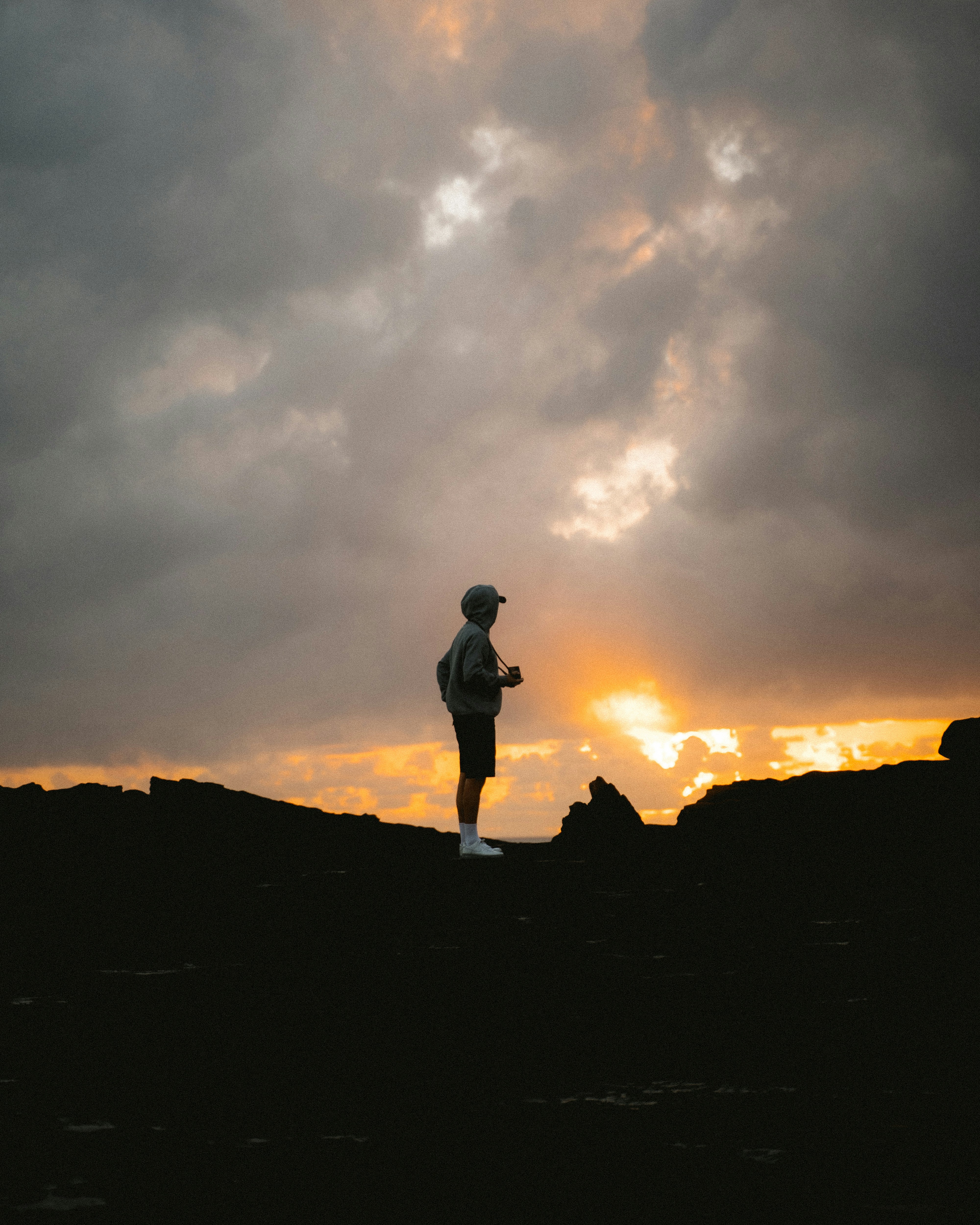 Man standing on rocky terrain at sunset