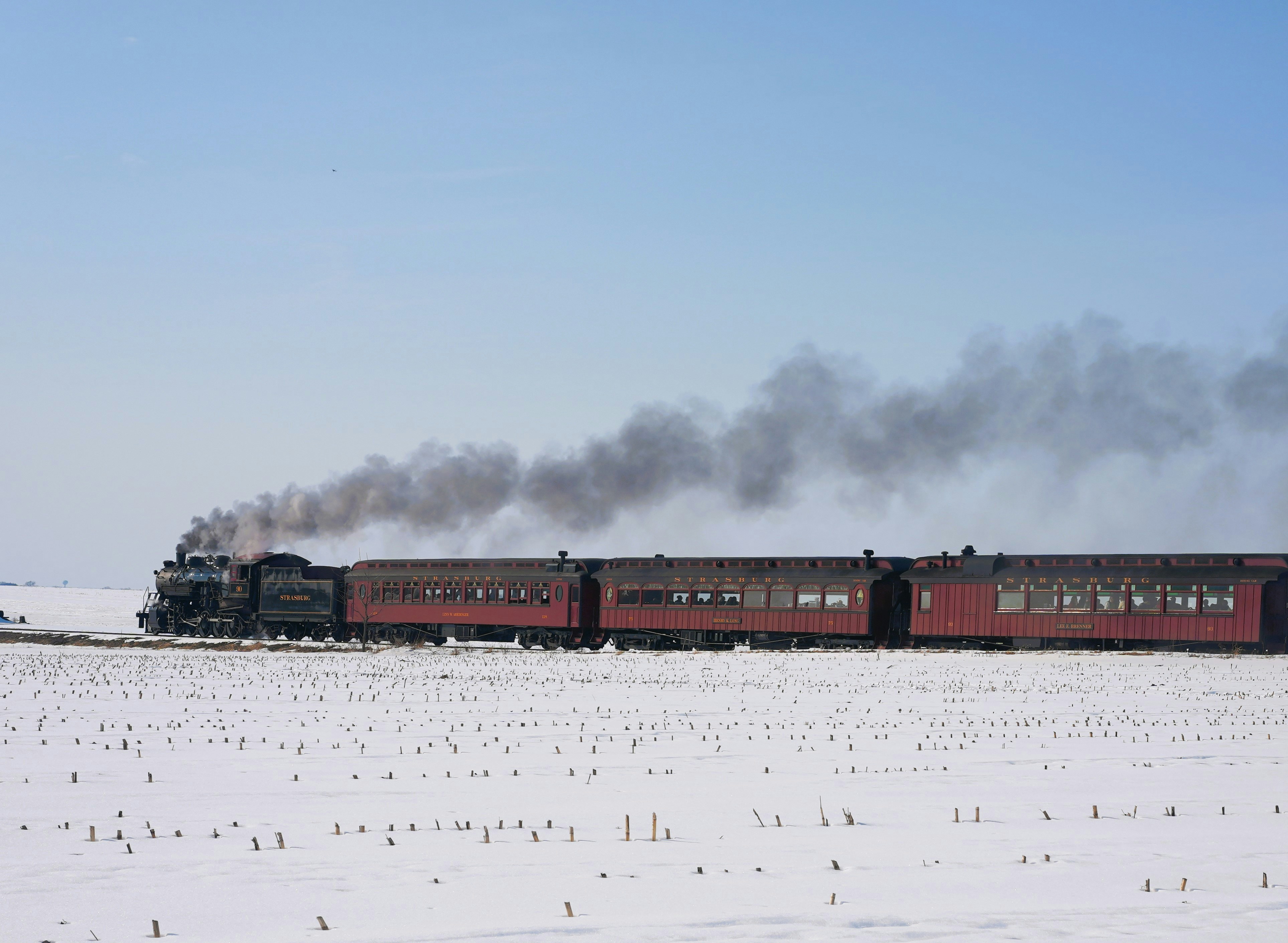 A vintage train travels through a snowy landscape.