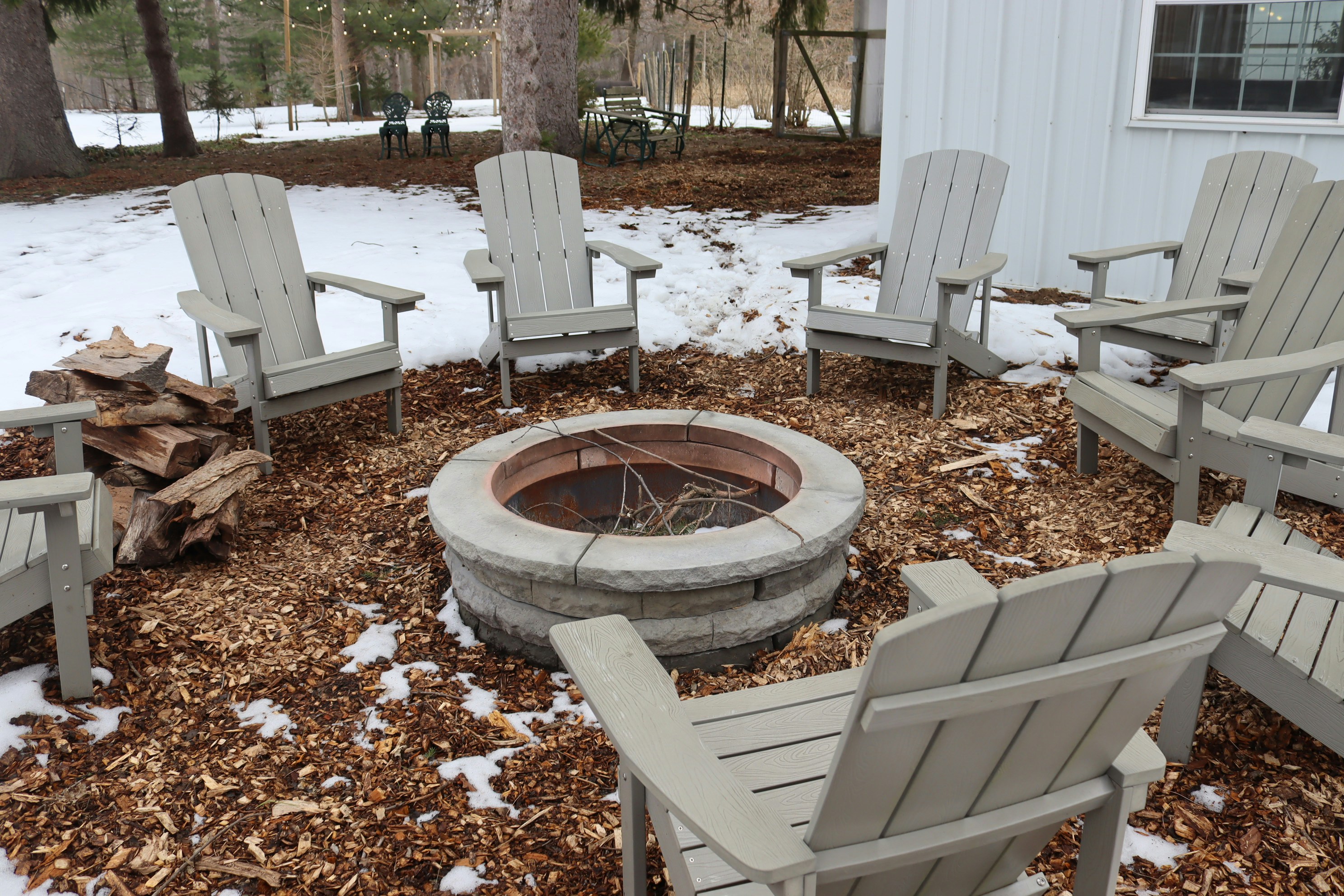 Adirondack chairs arranged around a stone fire pit
