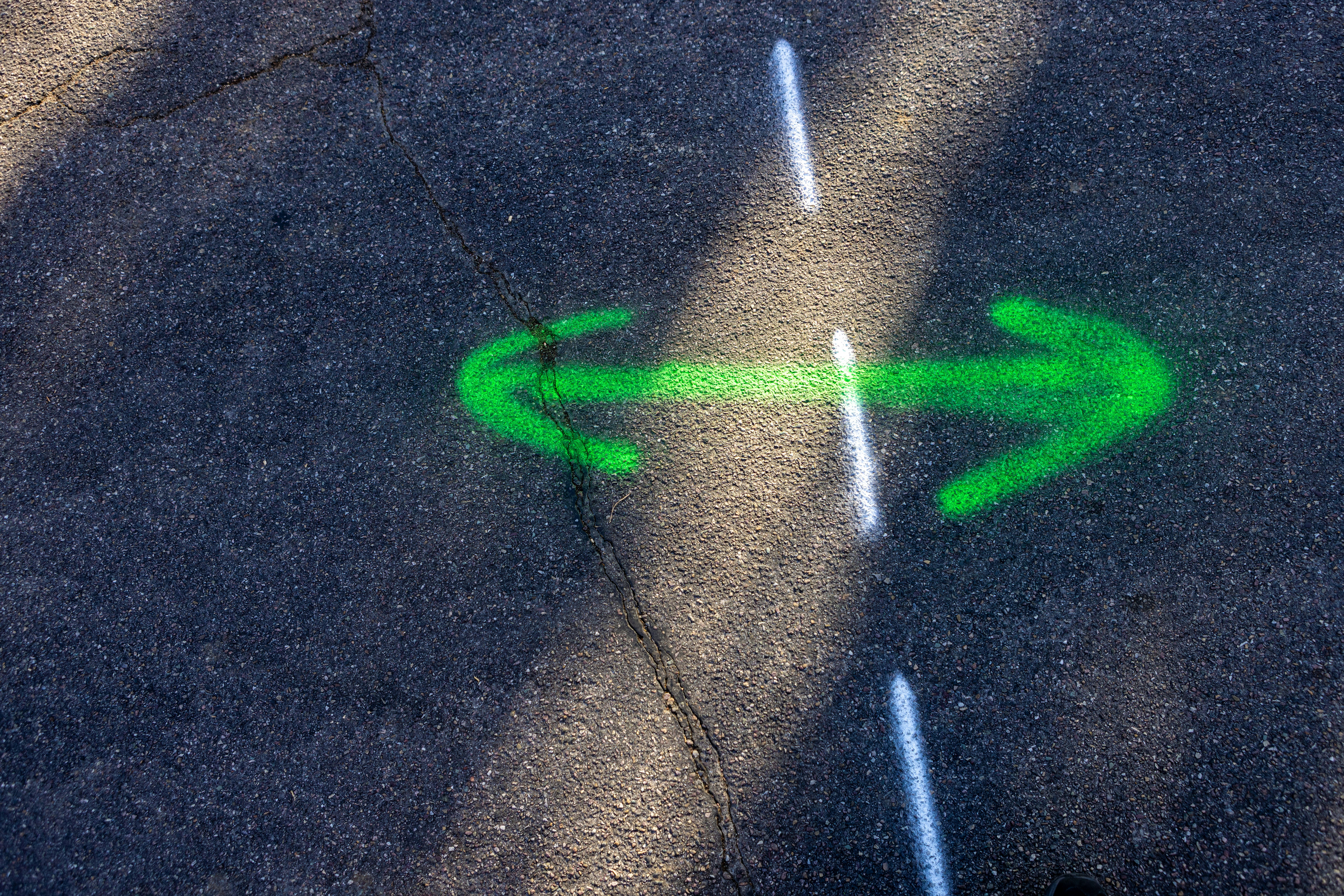 Green arrows point in opposite directions on asphalt.