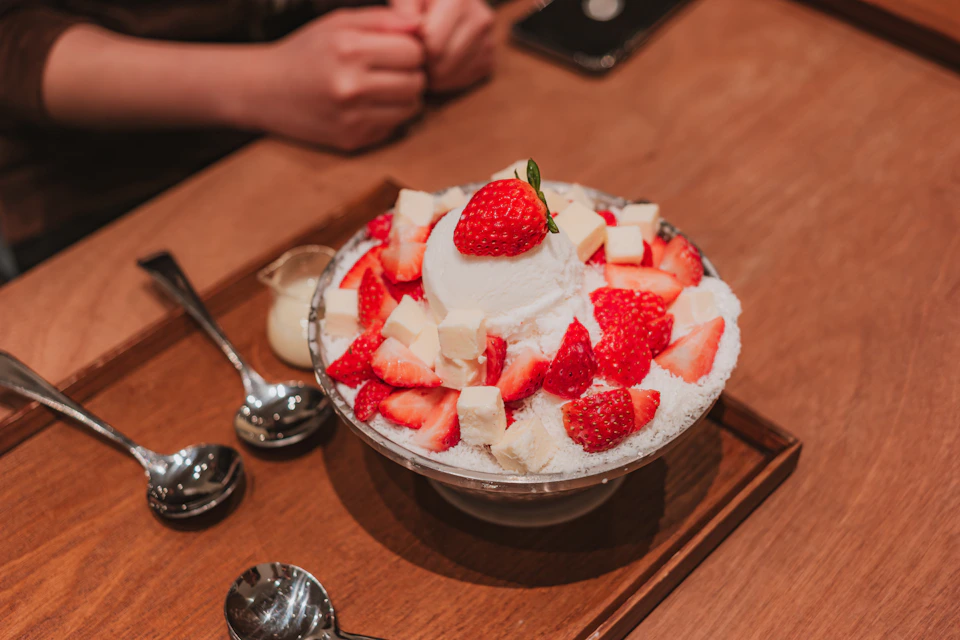 A bowl of bingsu, shaved ice with strawberries and cream