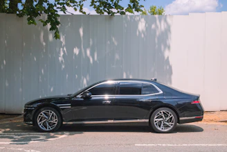A sleek black sedan parked against a white wall.