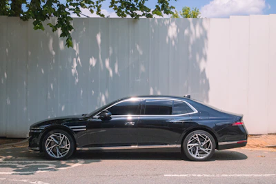 A sleek black sedan parked against a white wall.
