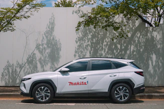 White suv with makita logo parked by wall