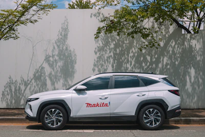 White suv with makita logo parked by wall