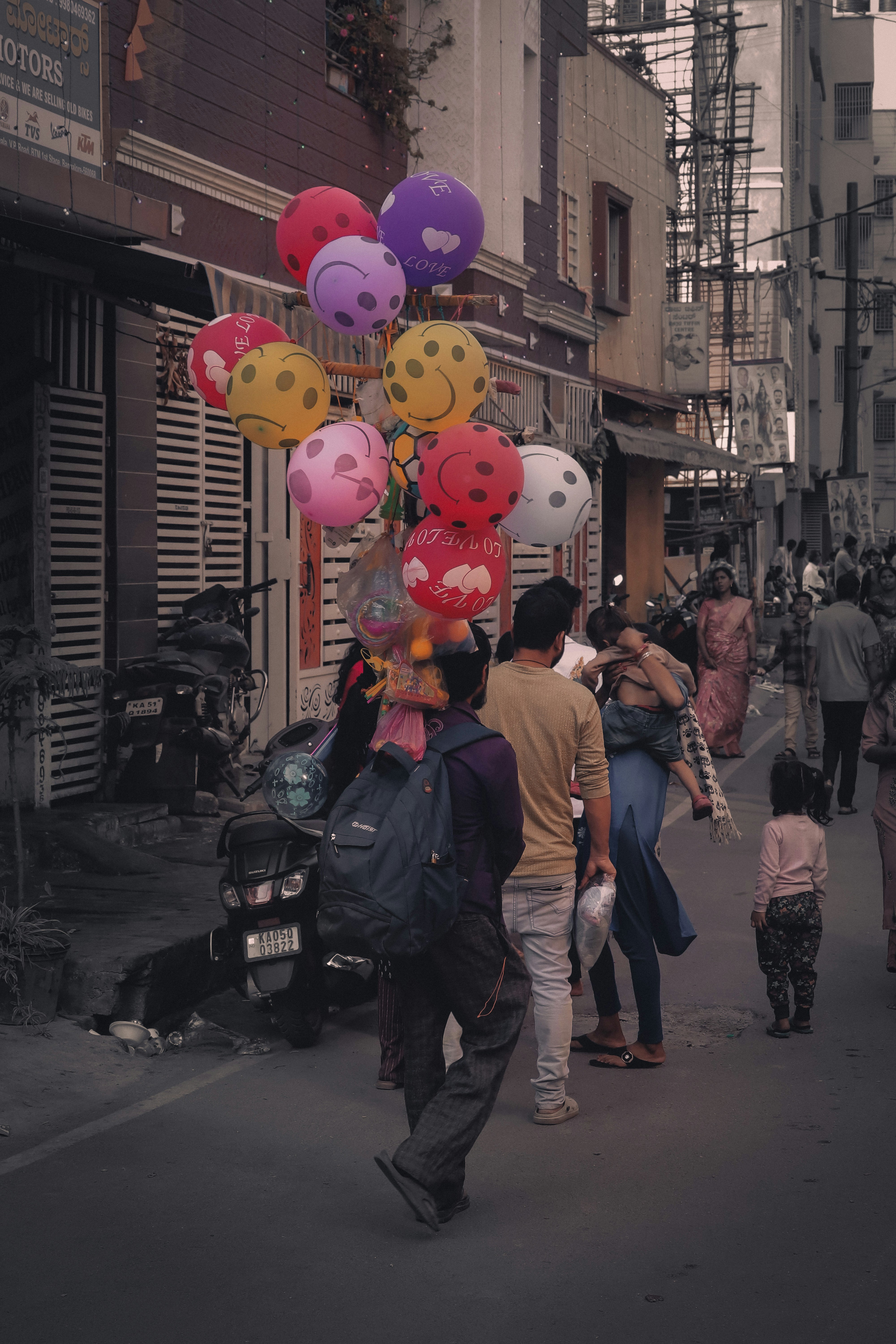 Balloons with smiley faces float on a street.