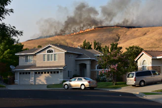 Wildfire burns a dry hillside near suburban homes.
