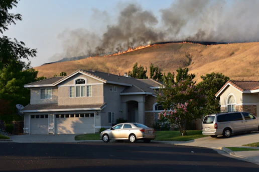 Wildfire burns a dry hillside near suburban homes.