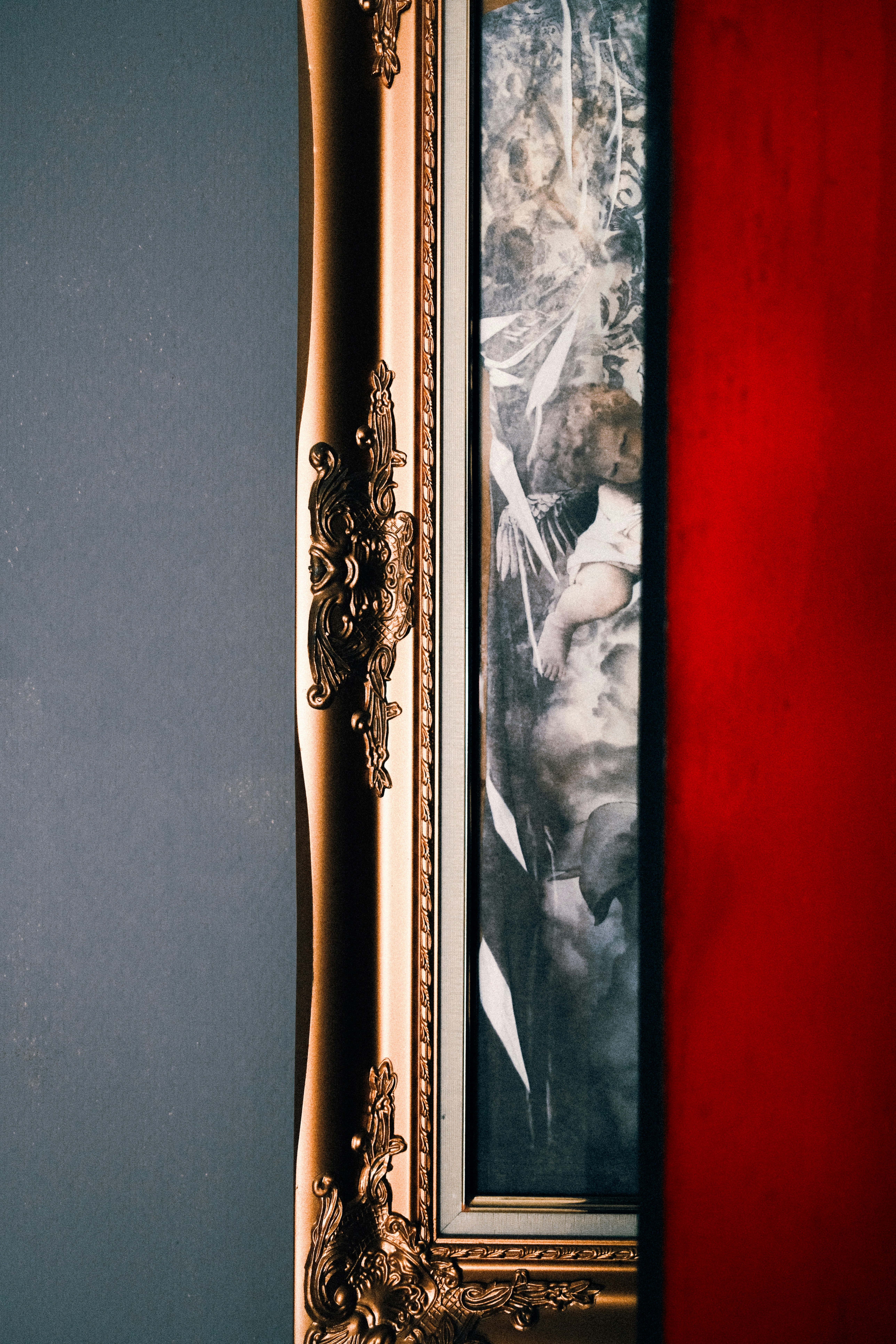 Cadre doré orné avec œuvres d’art entre murs rouges et gris