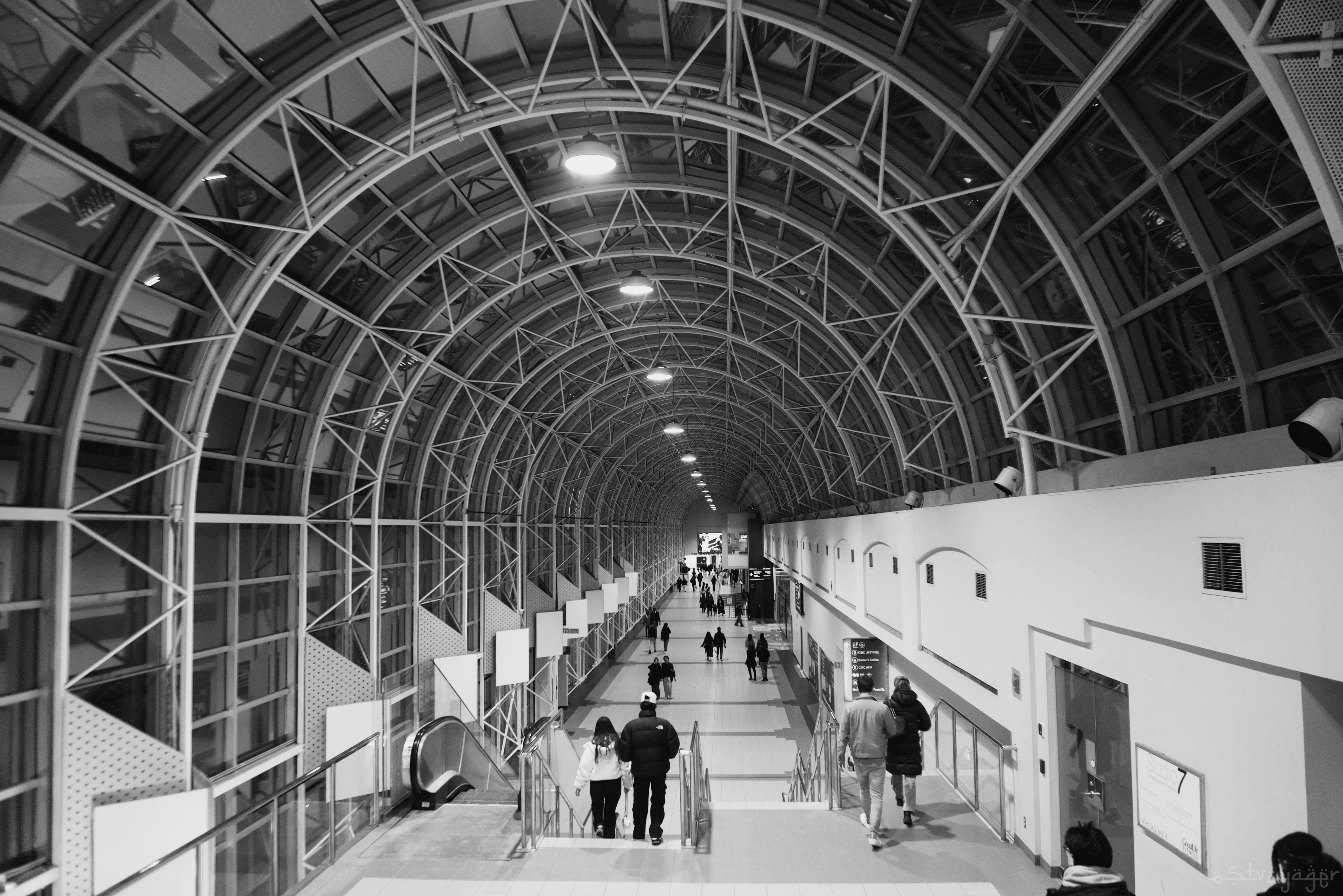 Personas caminando por un pasillo moderno y arqueado