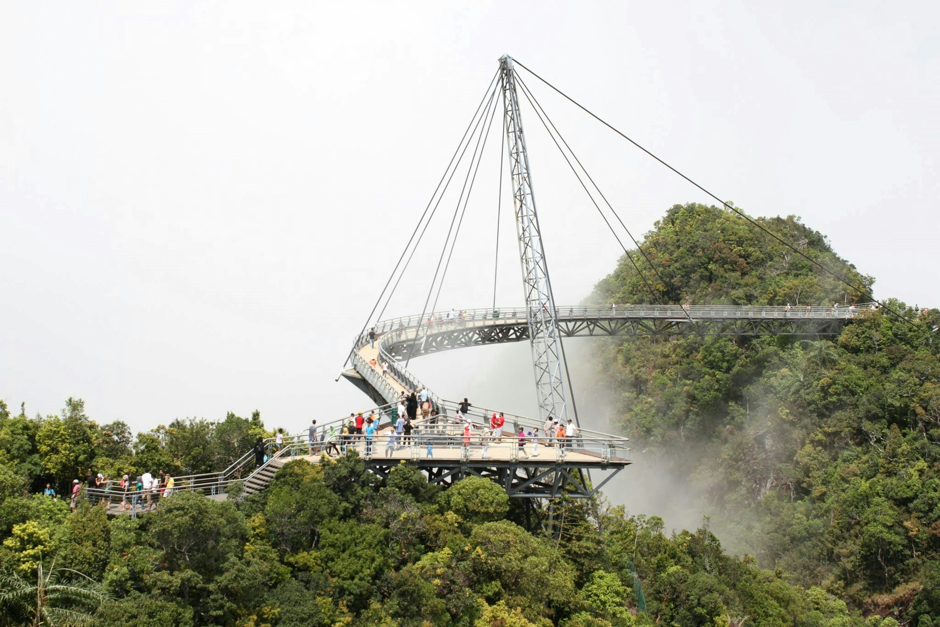 Curved pedestrian bridge on a lush, misty mountainside