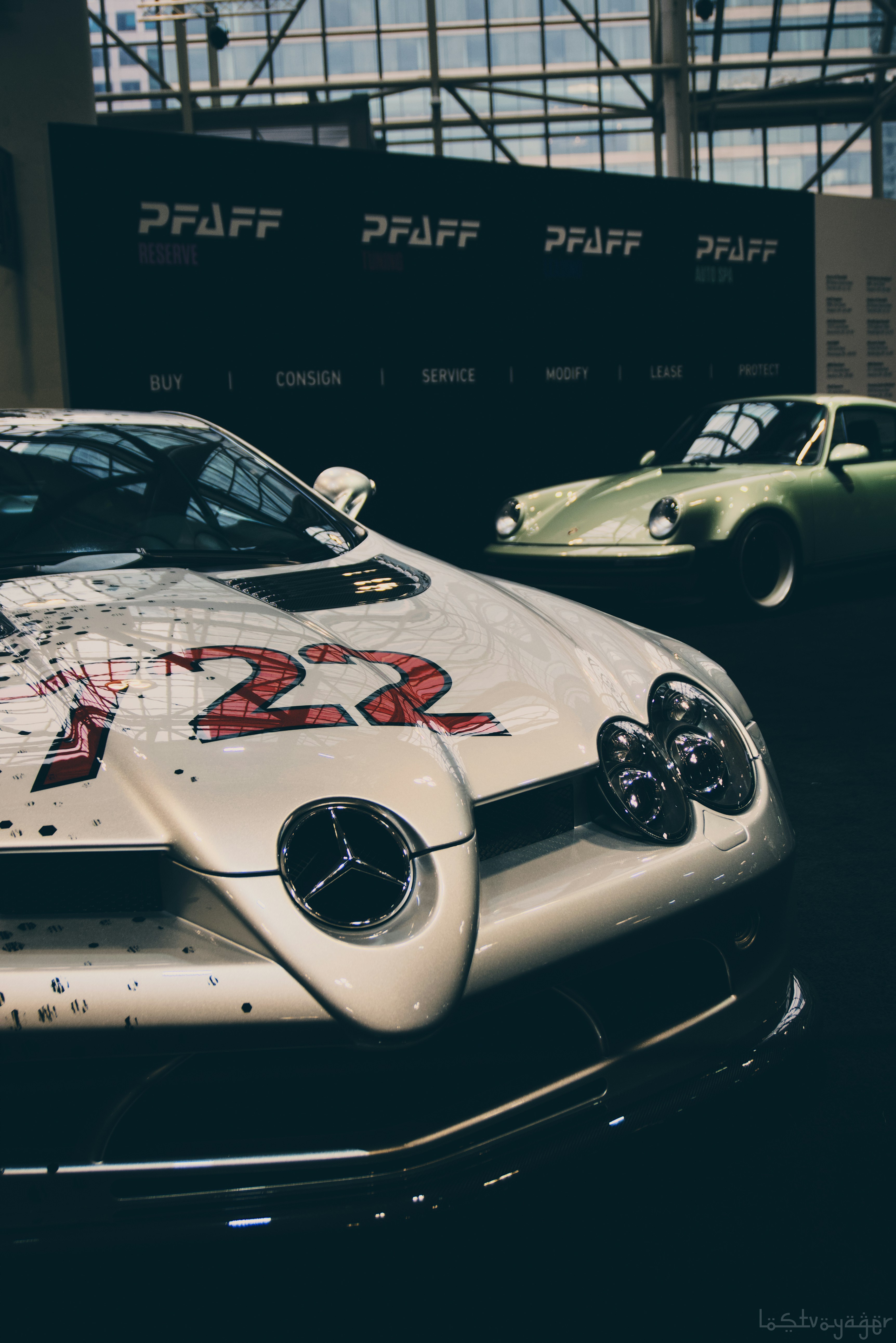 Dos coches vintage exhibidos en interiores con números de carrera.