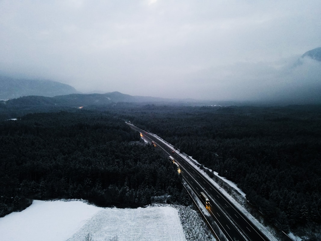 暮色中穿越森林的高速公路與點亮的車燈