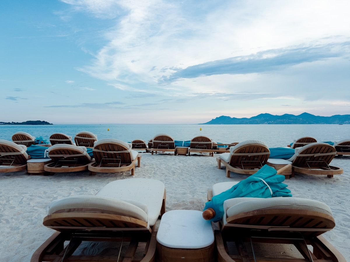 Empty lounge chairs on a sandy beach overlooking the ocean.