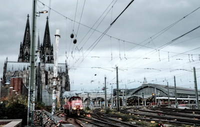 Train approaching a cathedral and station under cloudy sky