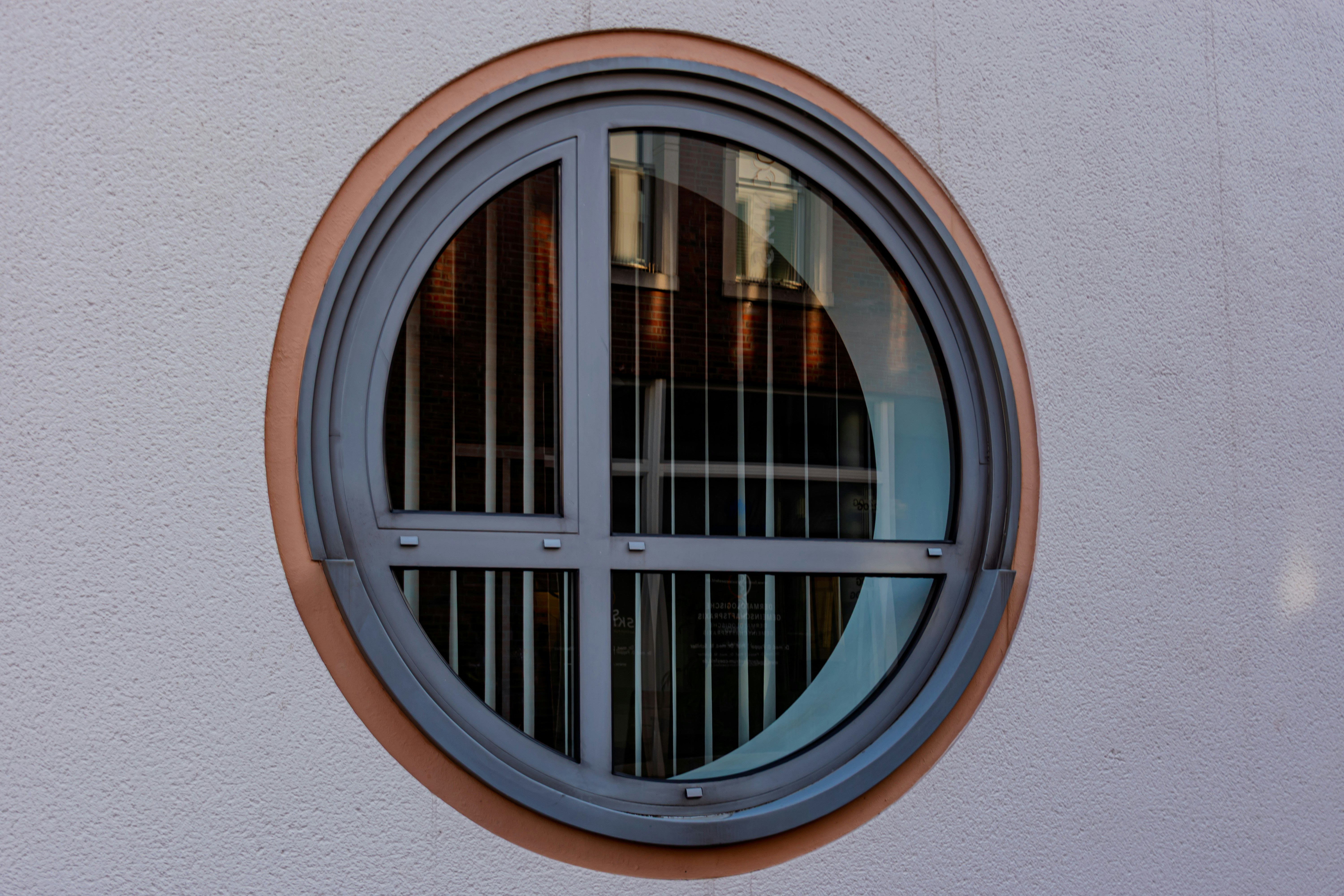 Circular window with metal bars on a white wall.