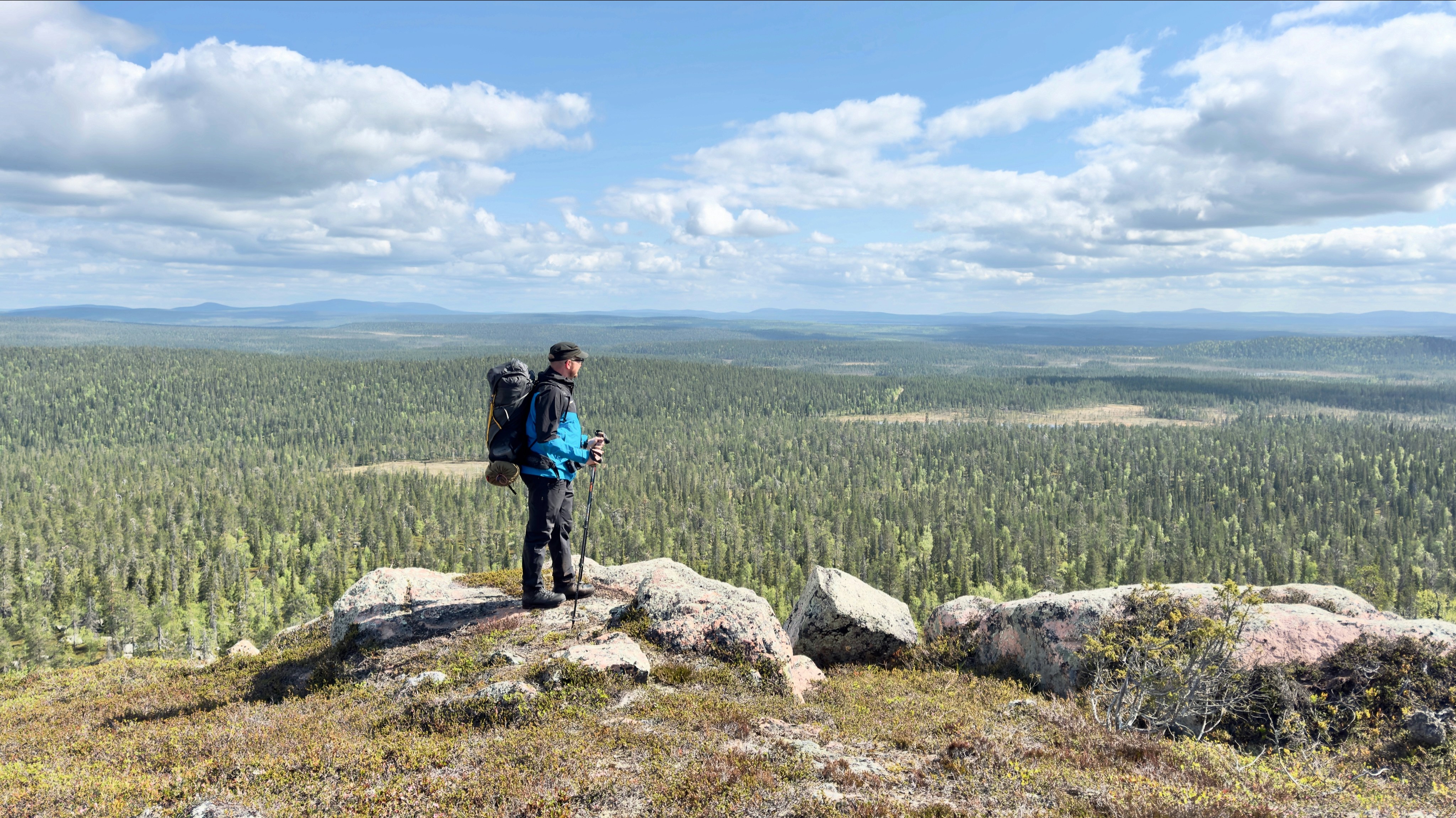 Hiker with backpack on rocky outcrop overlooking forest