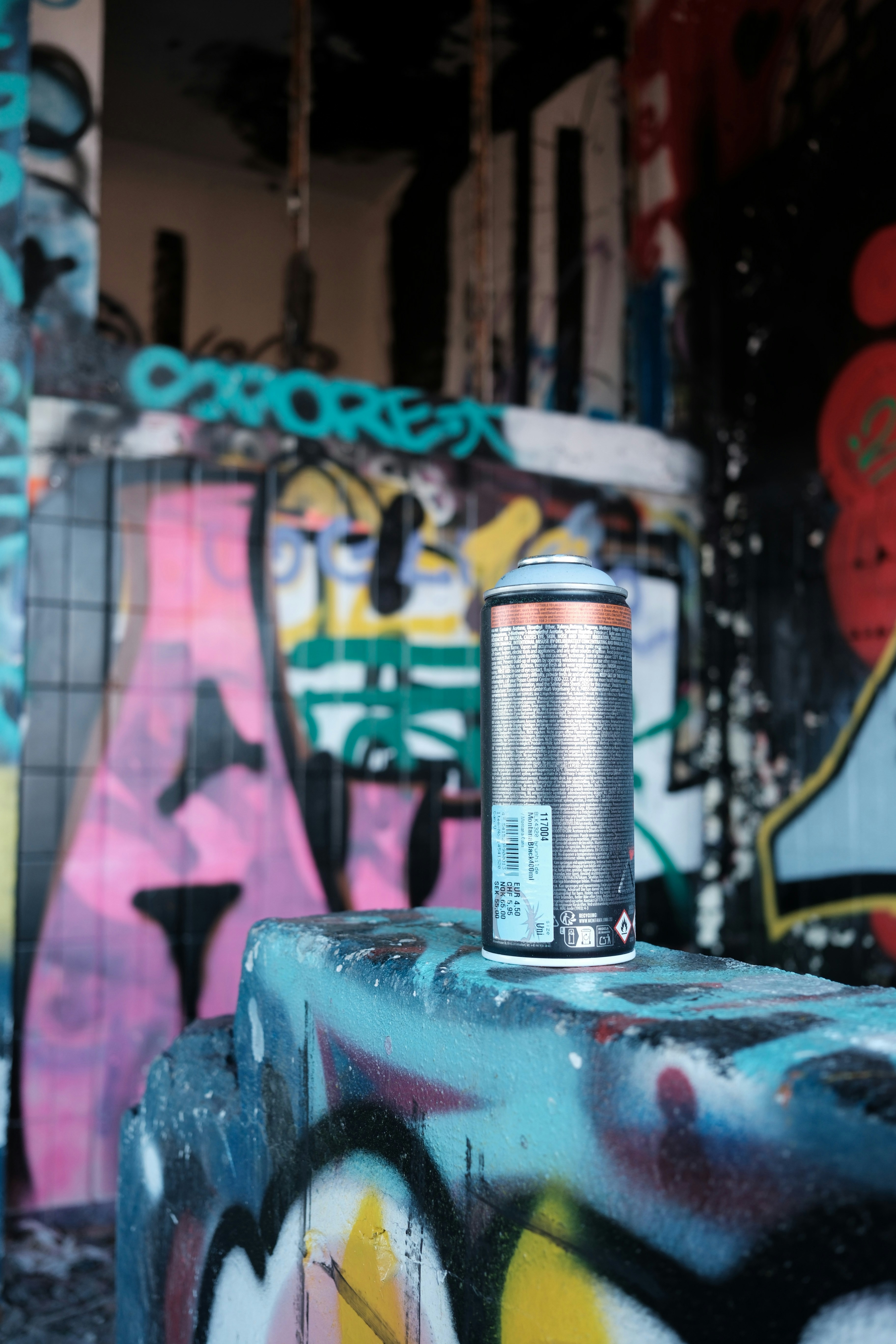 La bombe de peinture repose sur du béton couvert de graffitis.