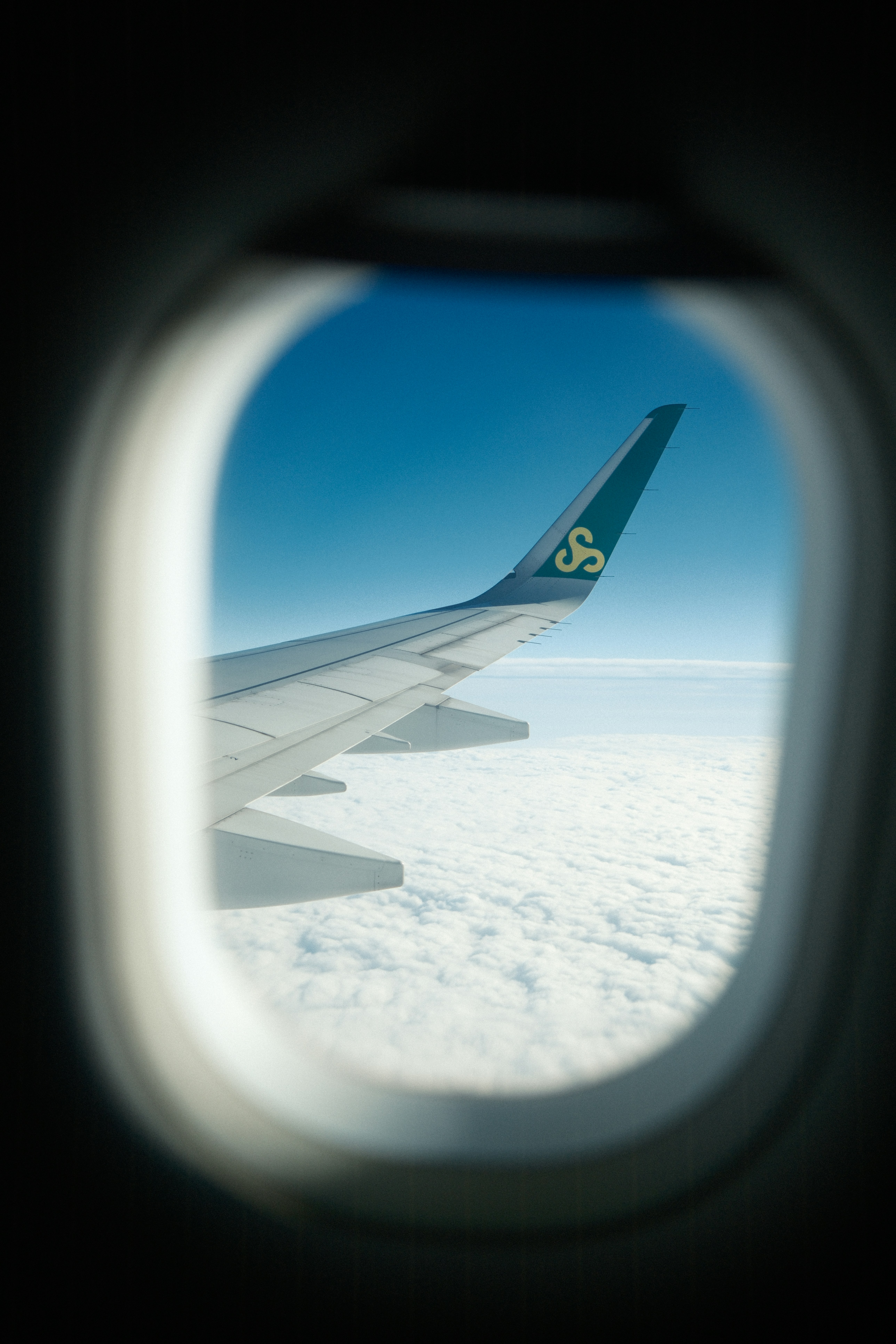 Airplane wing seen through a window above clouds
