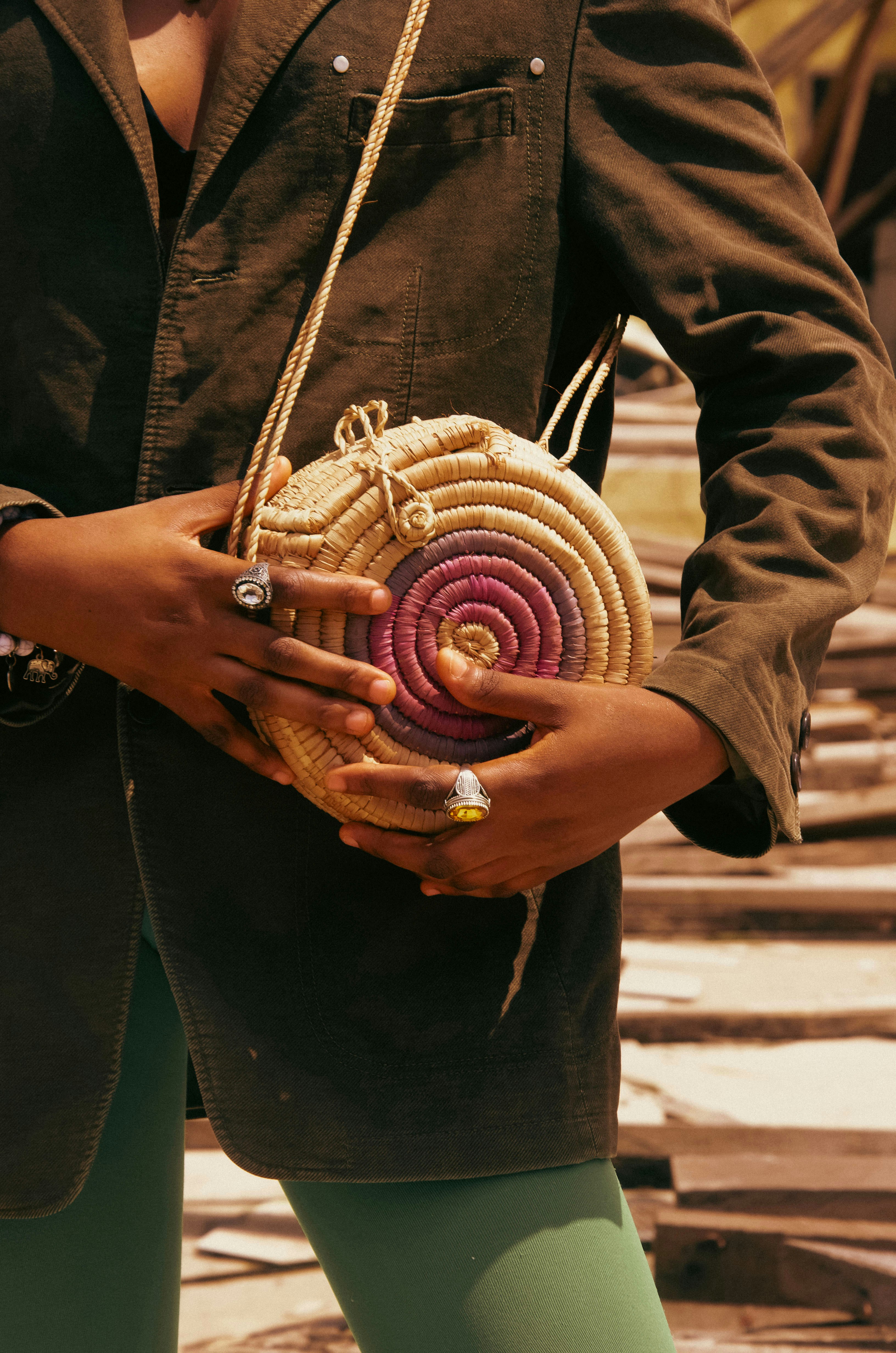 Mujer con chaqueta marrón sosteniendo una bolsa redonda tejida.