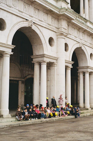 Children sitting on steps of grand building