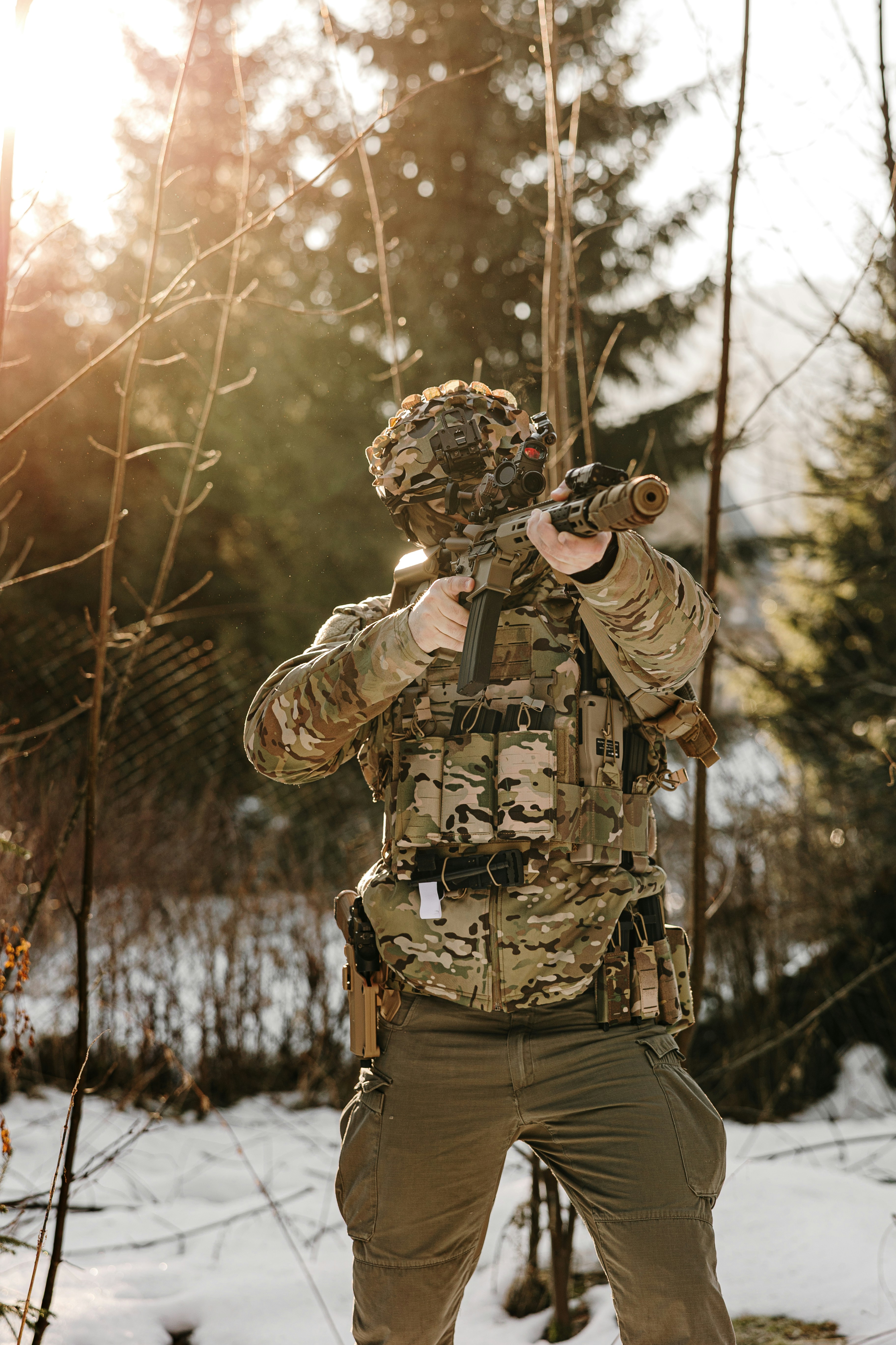 Soldat in Tarnkleidung zielt im schneebedeckten Wald mit Zielgewehr