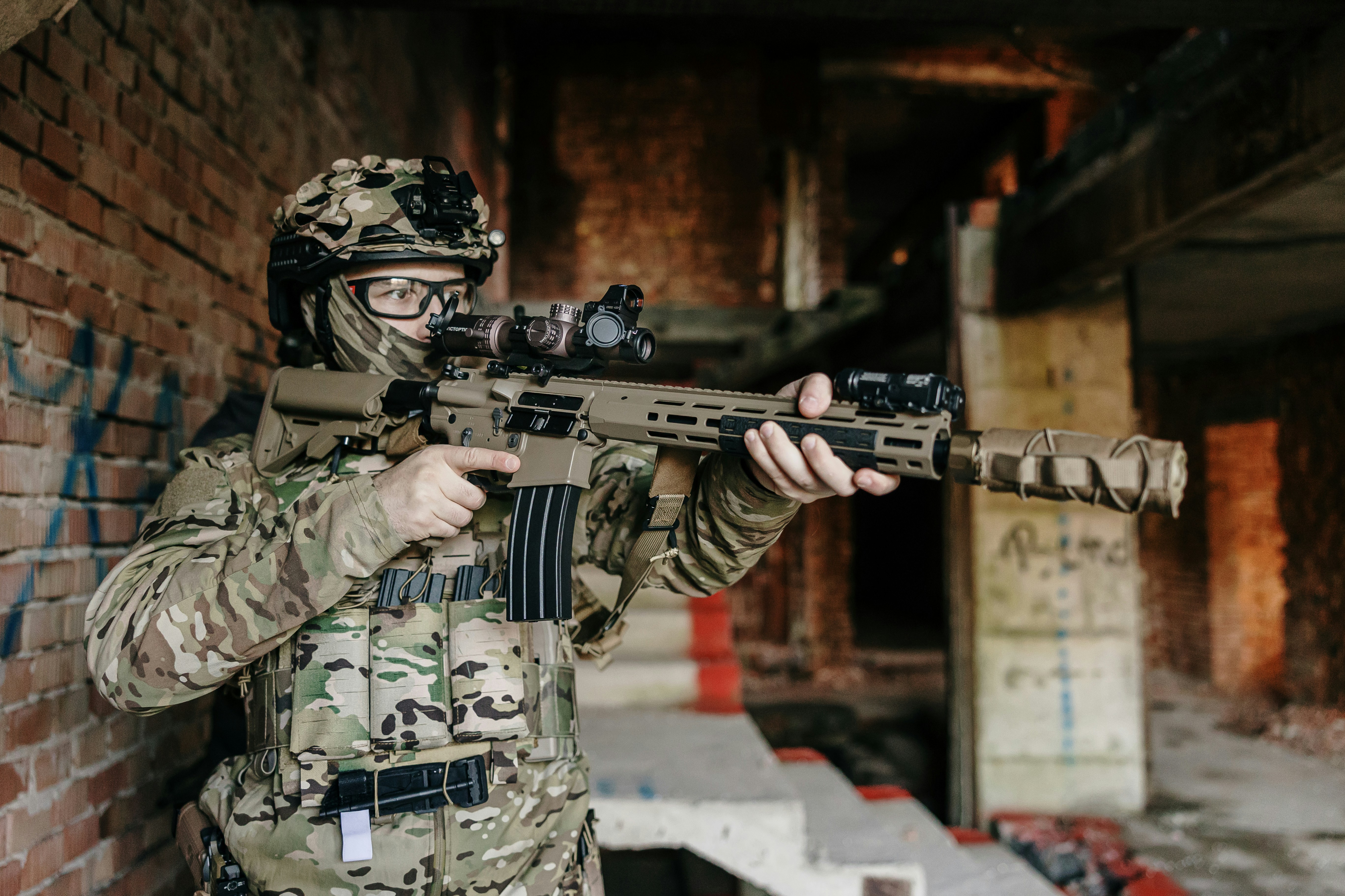 Soldat in Tarnkleidung hält ein Gewehr drinnen.