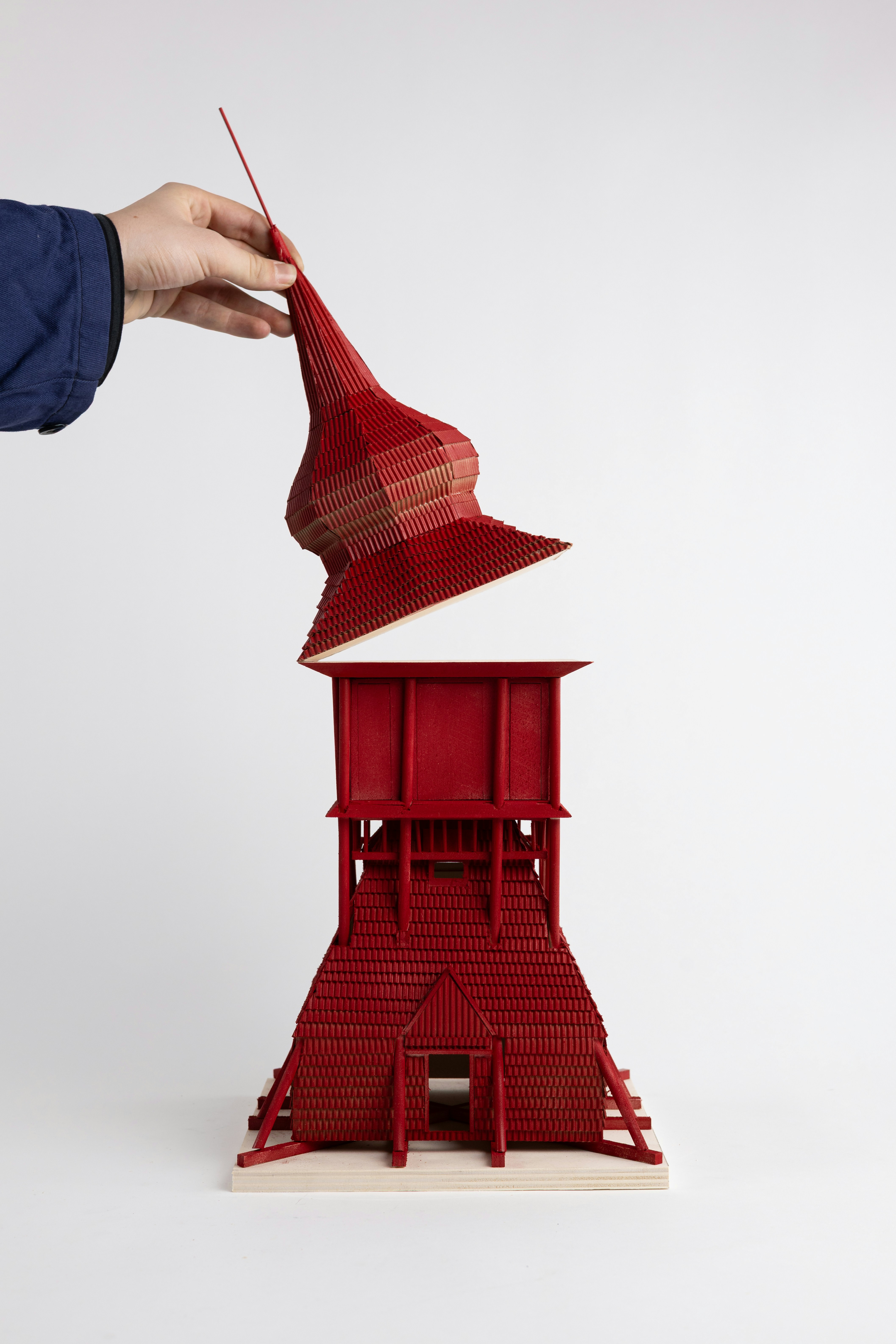 Hand placing red pagoda roof on tower