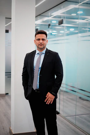 A man in a suit stands in a modern office.