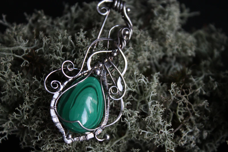 Colgante de filigrana de plata con una malaquita verde en forma de lágrima sobre liquen