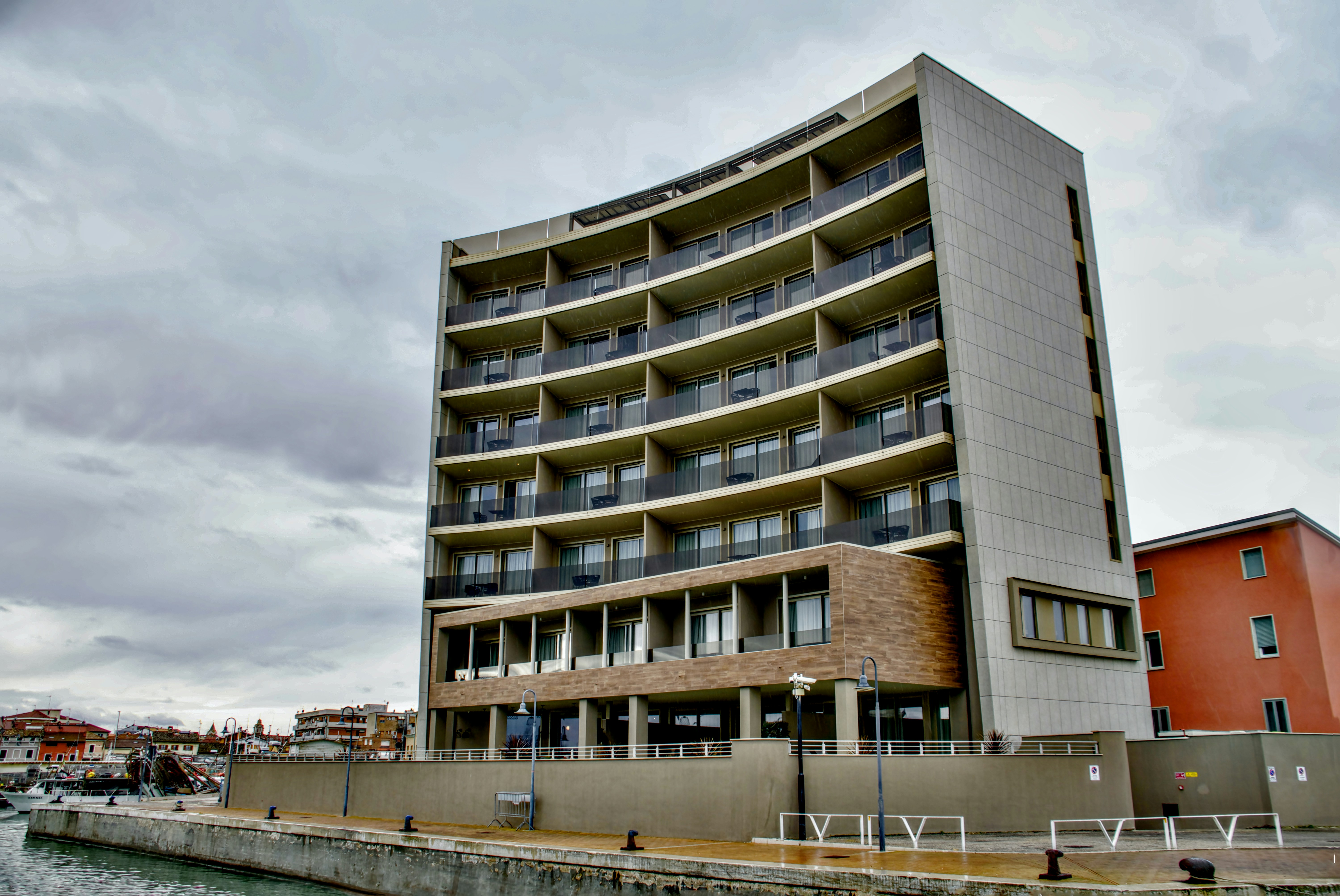 Modern curved building by the waterfront under cloudy skies