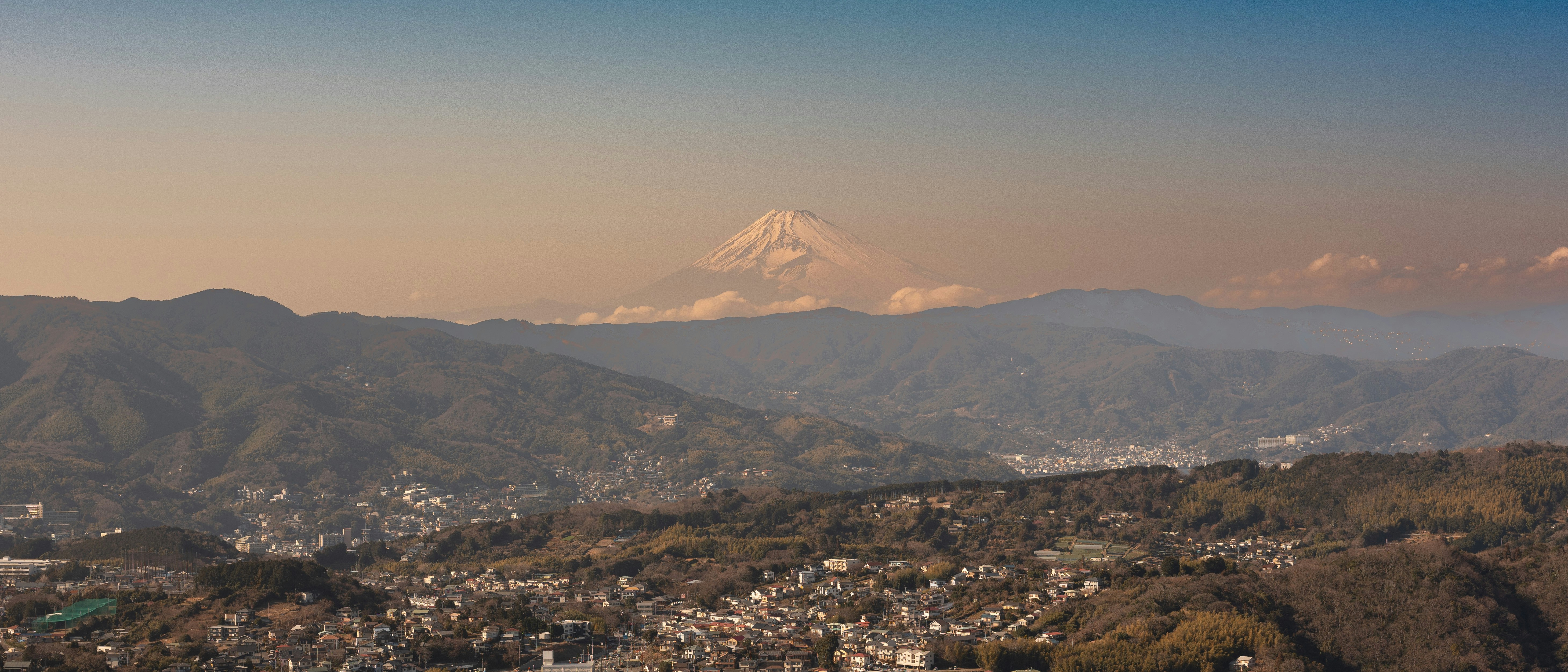 Snow-capped mountain visible over rolling hills at sunset.